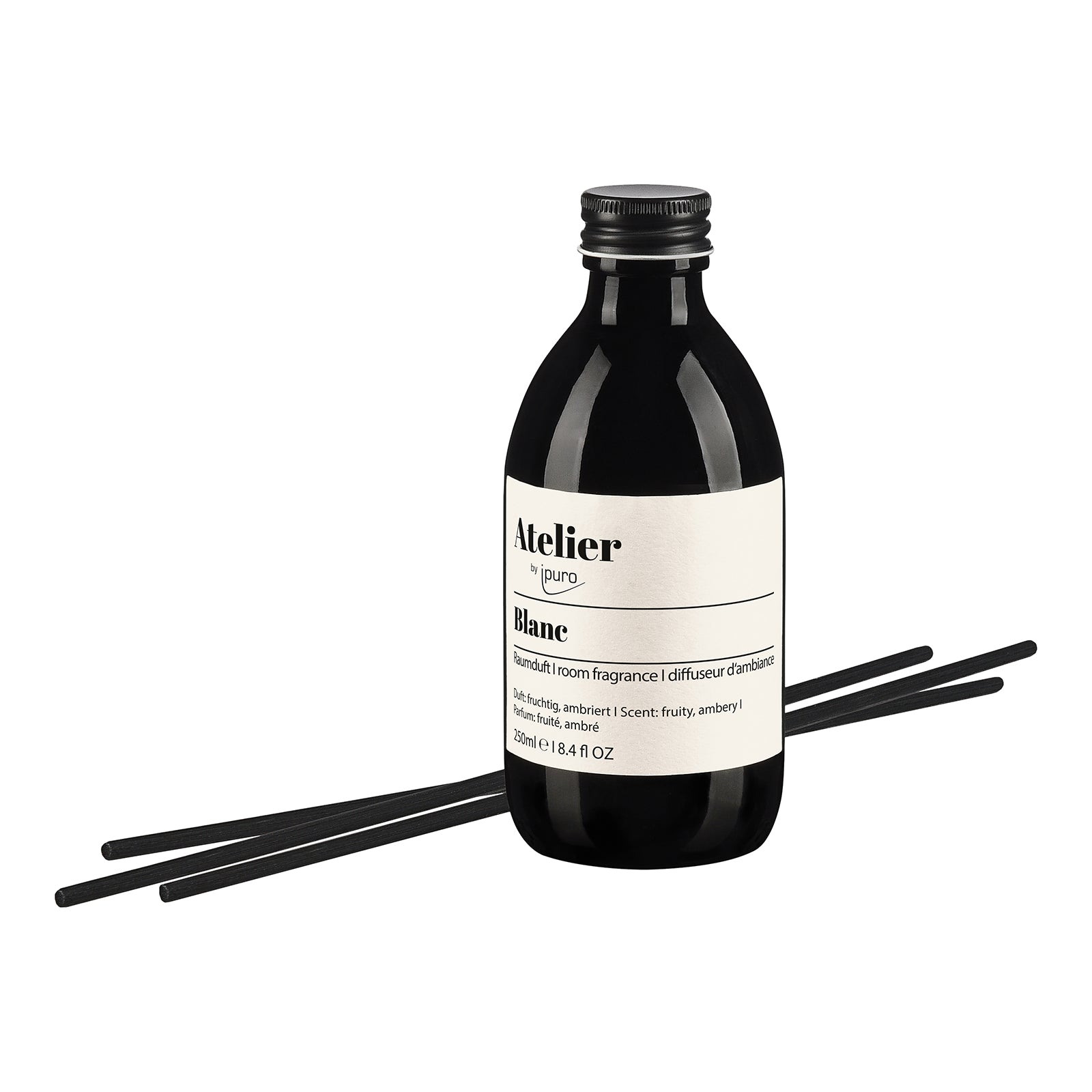 Eine dunkle Glasflasche mit der Aufschrift Atelier by ipuro blanc Raumduft von ipuro, mit vier schwarzen Stäbchen, verströmt einen klaren Duft und florale Akzente, dargestellt vor einem weißen Hintergrund.