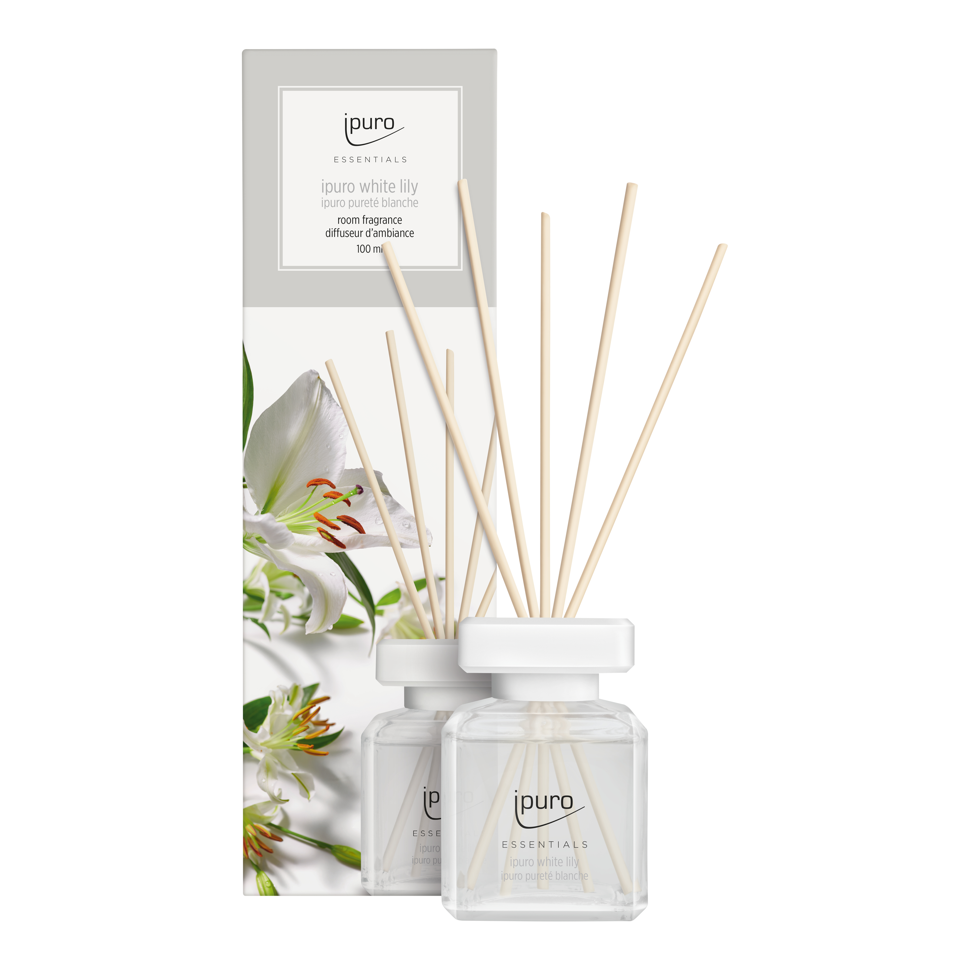 Ein klarer Glasdiffusor mit Holzstäbchen und einem Etikett mit der Aufschrift "ipuro white lily" steht vor seiner Verpackung, die weiße Lilien und das ESSENTIALS ipuro white lily Raumduft-Branding für ein florales Dufterlebnis zeigt.