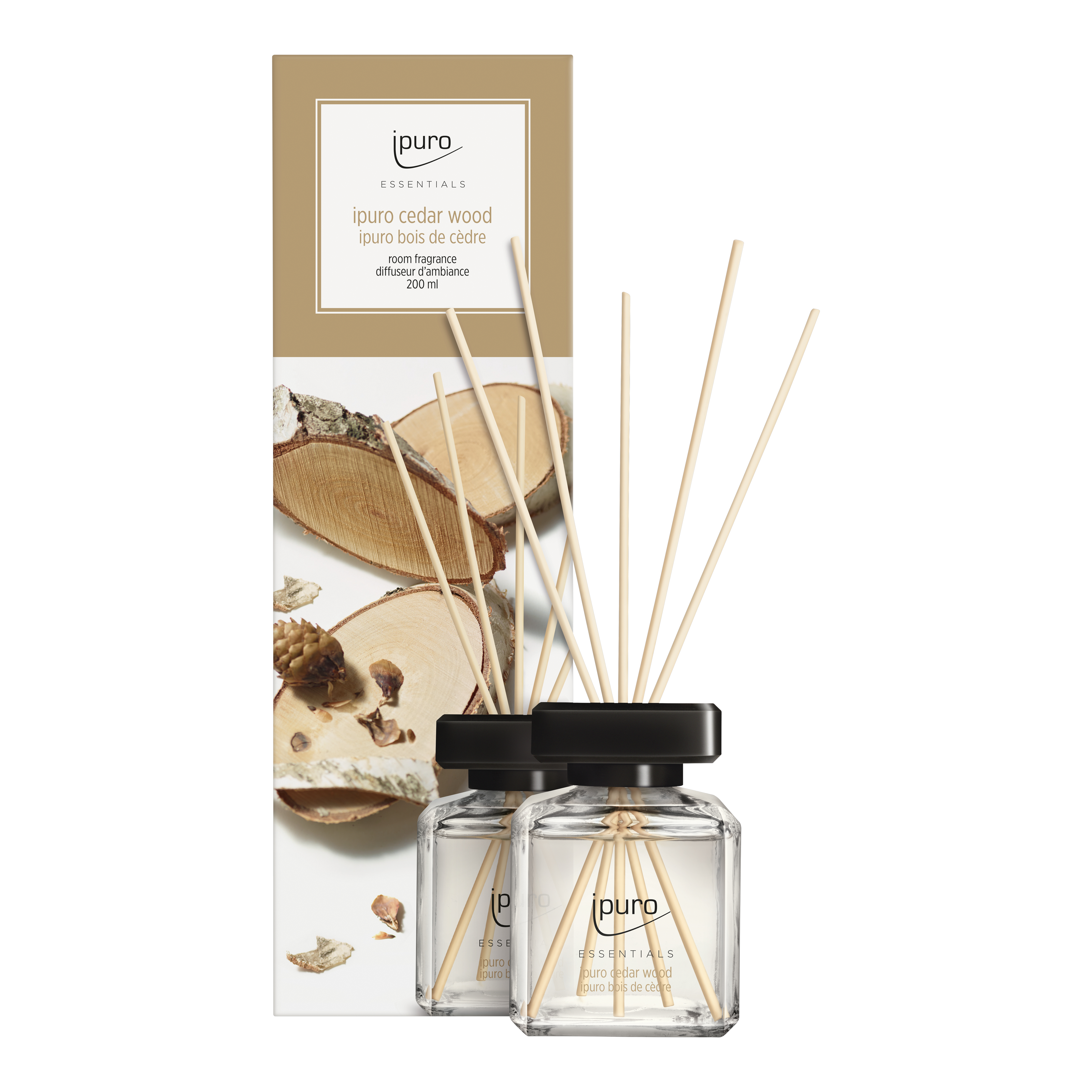 Two ESSENTIALS ipuro cedar wood Raumduft glass reed diffusers with black caps and wooden sticks stand before packaging decorated with Zedernholz and pinecones, evoking a pleasantly warm and spicy fragrance.