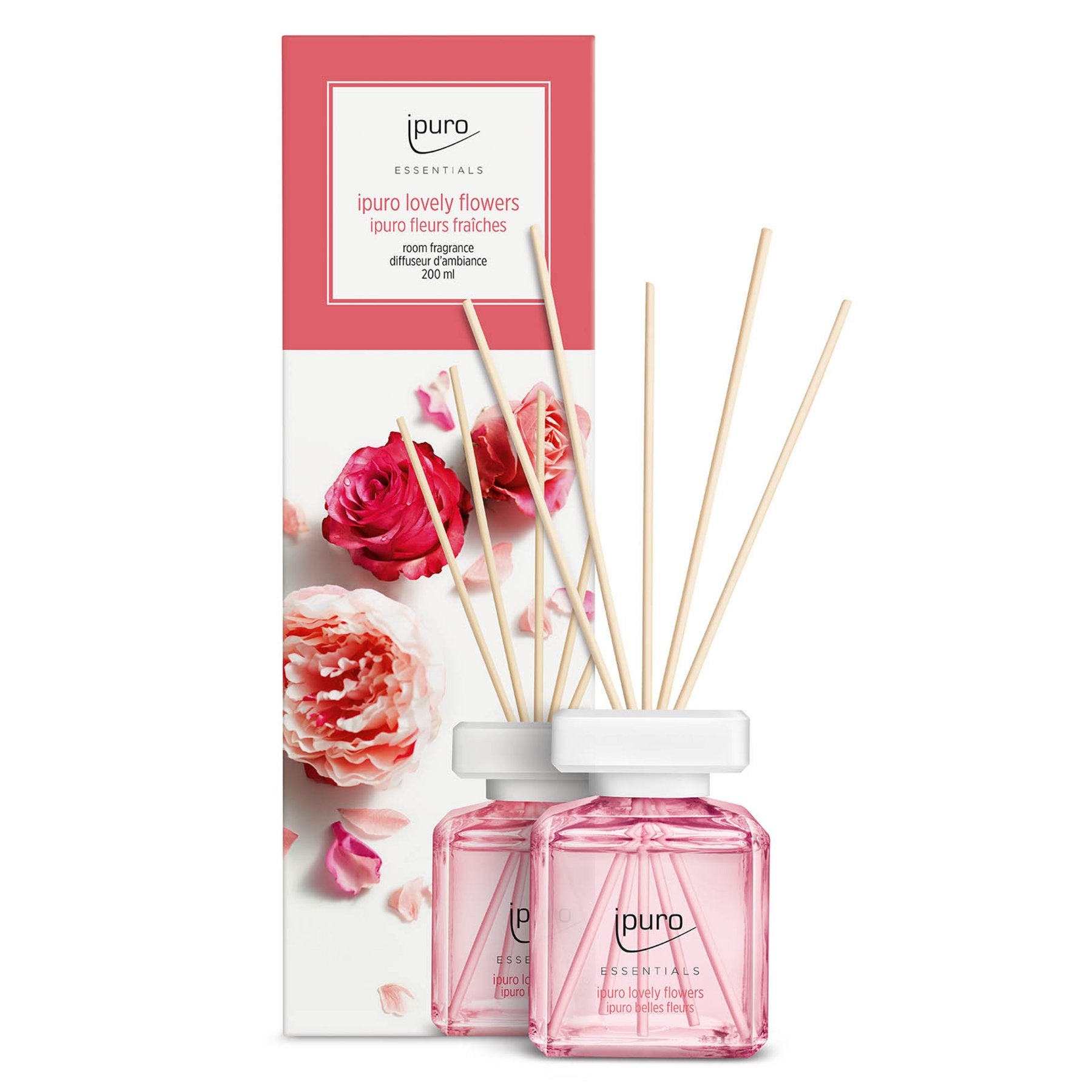 Zwei gläserne Diffusorflaschen mit rosafarbener Flüssigkeit und Holzschilfrohr stehen vor einem Blumenkasten. Auf dem Etikett steht ipuro ESSENTIALS lovely flowers Raumduft, mit Noten von Rose und Maiglöckchen von ipuro.
