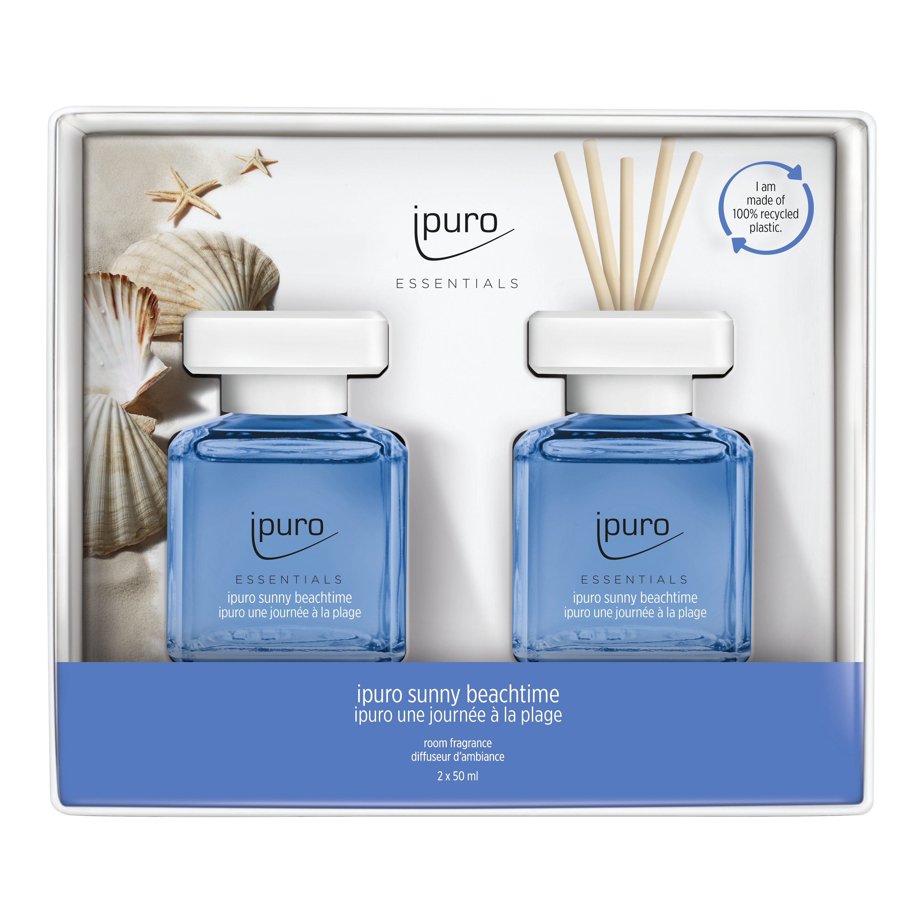 Das ESSENTIALS ipuro sunny beachtime Raumduft-Set von ipuro enthält zwei blaue Flaschen mit weißen Kappen, Schilfrohrstäbchen, Muscheldekorationen und duftet nach Jasmin und Grapefruit. Die Verpackung hebt die Verwendung von recyceltem Kunststoff hervor.