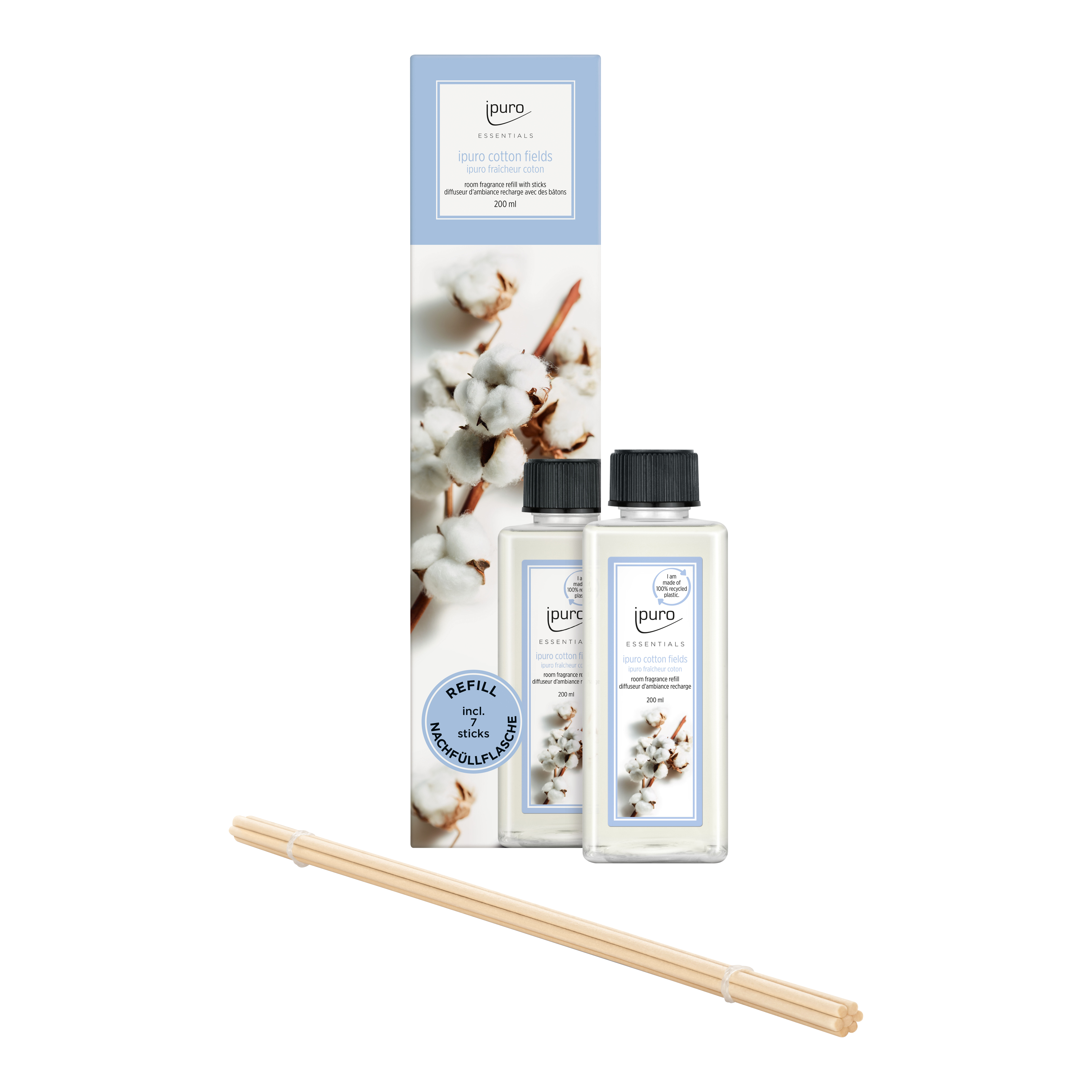 Zwei durchsichtige Flaschen ESSENTIALS ipuro Baumwollfelder Raumduft-Nachfüller mit weißem Etikett, ausgestellt vor einer hohen Schachtel mit Baumwollblüten. Davor sind mehrere Schilfrohr-Diffusor-Stäbchen für einen frischen, pudrigen Duft von ipuro angeordnet.