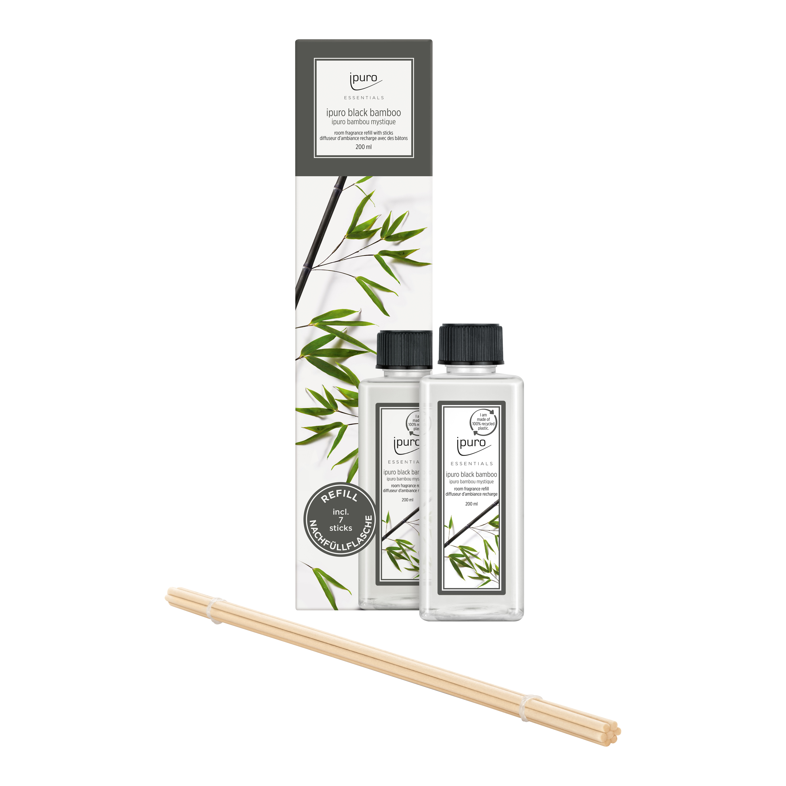Zwei durchsichtige Flaschen ESSENTIALS ipuro black bamboo Raumduft-Nachfüller von ipuro mit schwarzem Verschluss stehen neben einer weißen, mit Bambusblättern verzierten Box; davor befinden sich mehrere natürliche Schilfrohr-Diffusorstäbchen für einen frischen, pflanzlichen Duft.