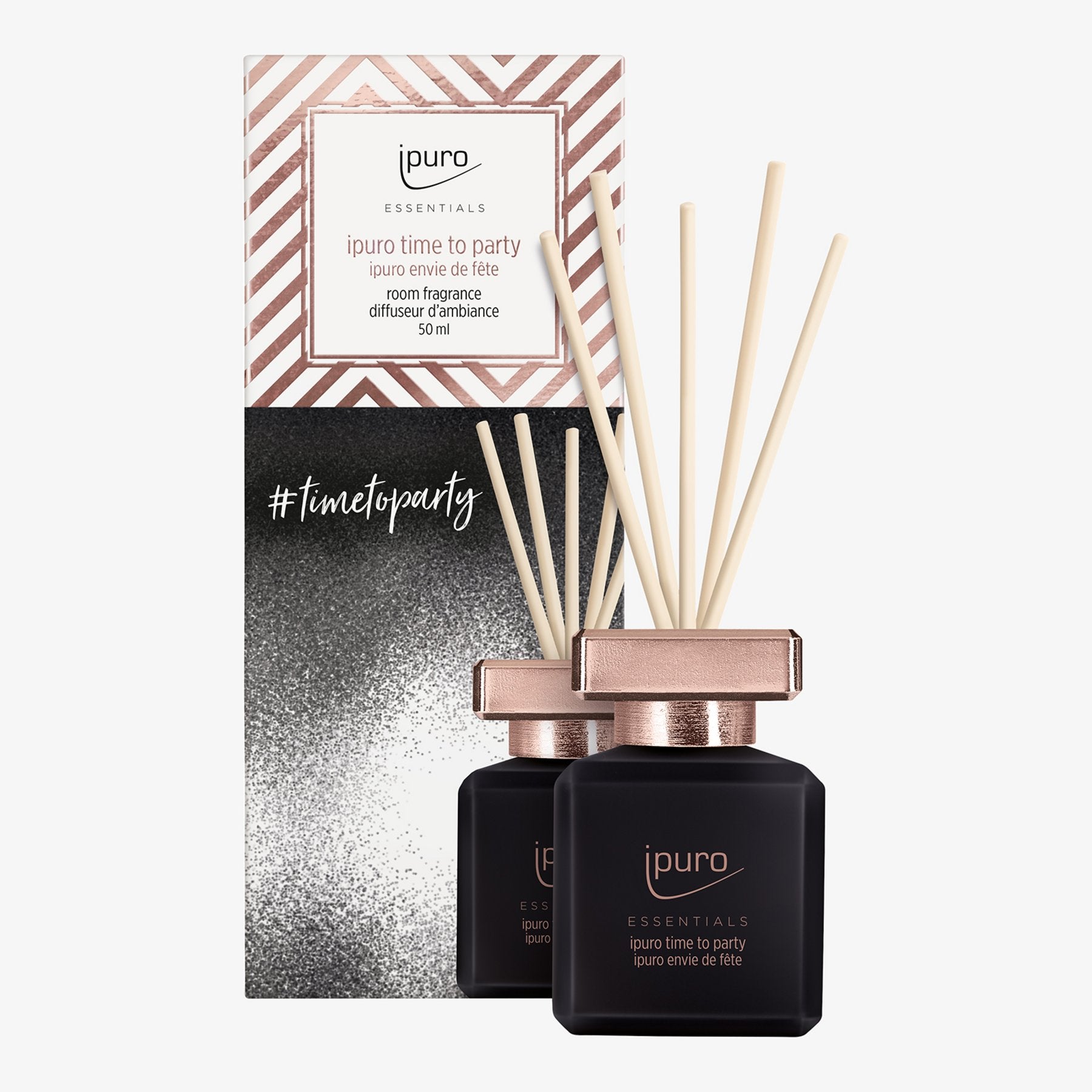 Die schwarz-roségoldenen ESSENTIALS ipuro time to party Raumduft-Flaschen mit Rattanstäbchen werden vor einer passenden, geometrischen, glitzernden ipuro #timetoparty-Box präsentiert.