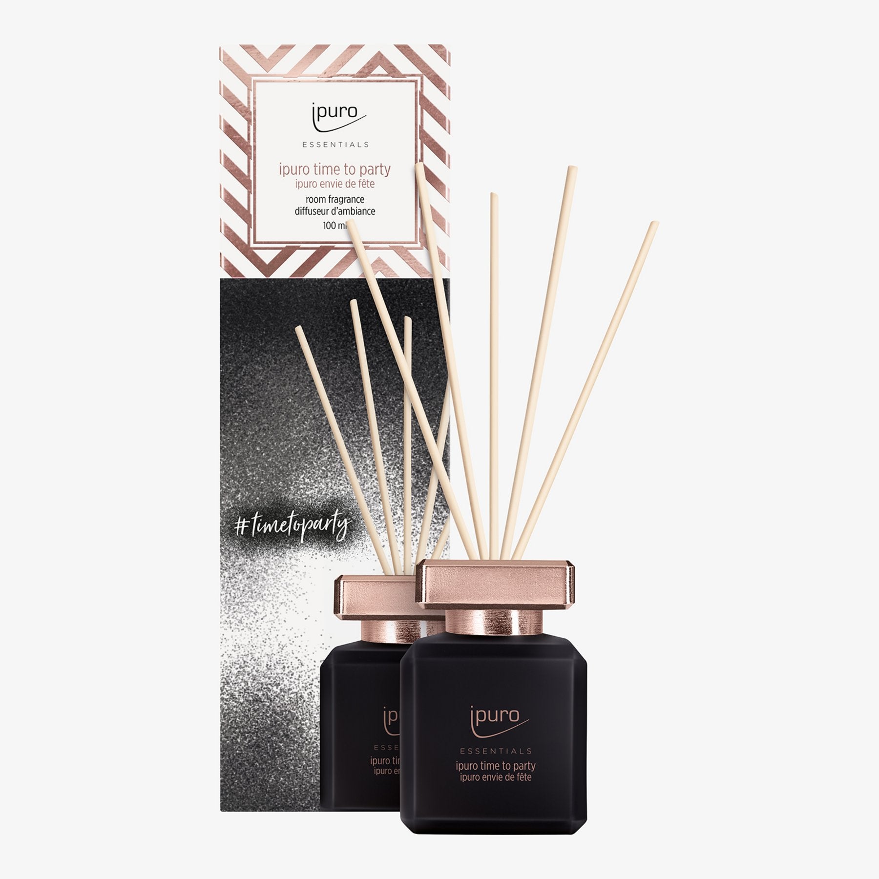 Ein schwarzer ESSENTIALS ipuro time to party Raumduft-Flakon von ipuro mit roségoldenem Verschluss und Schilfrohrstäbchen steht vor seiner stilvollen Schachtel, die mit Metallstreifen und dem Hashtag #timetoparty versehen ist.