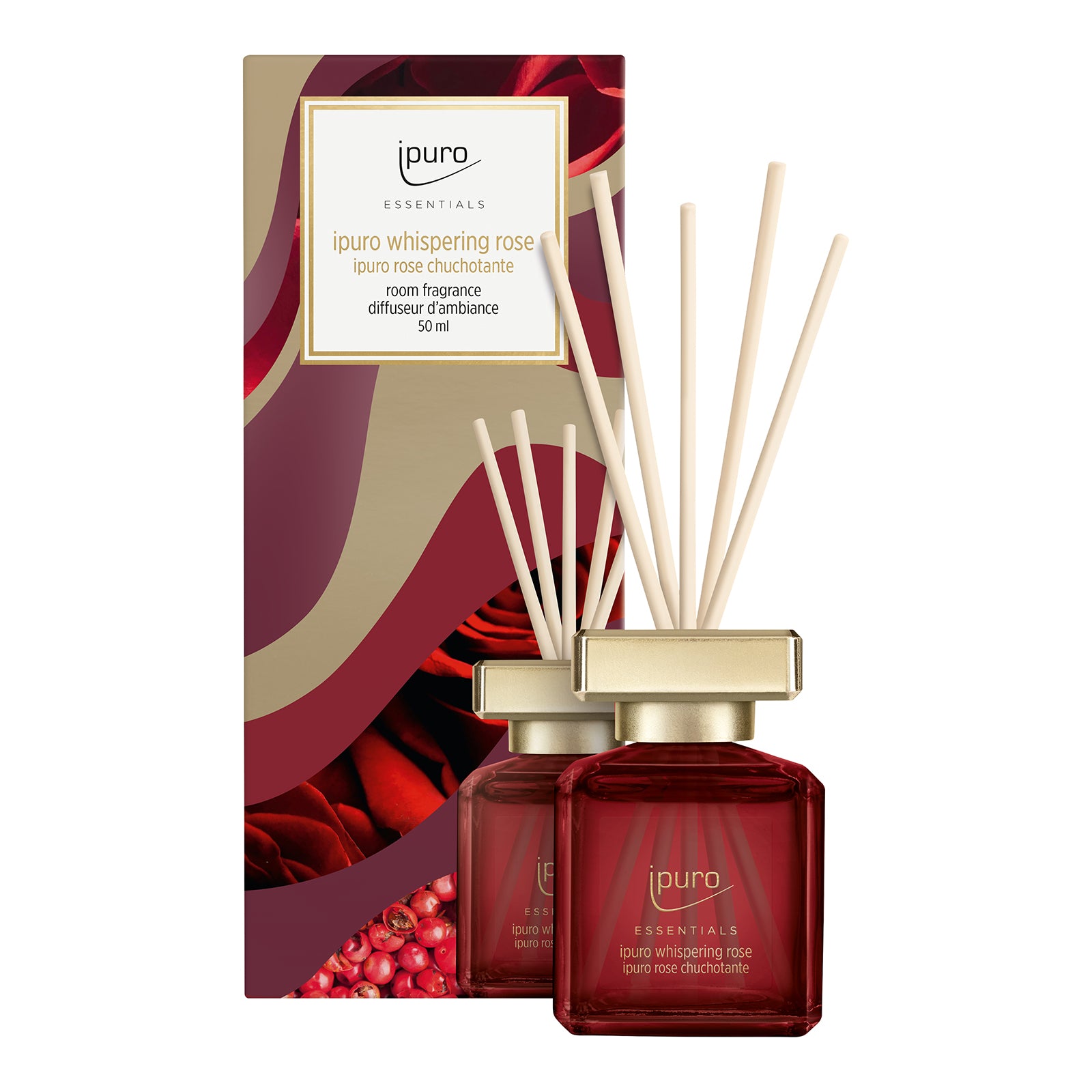 Ein roter Glasflakon von ESSENTIALS ipuro whispering rose Raumduft von ipuro mit beigen Diffusorstäbchen steht vor seiner gold-roten, mit Rosenblättern verzierten Schmuckdose. Fruchtige Noten und holzige Aromen schaffen ein einzigartiges Dufterlebnis.