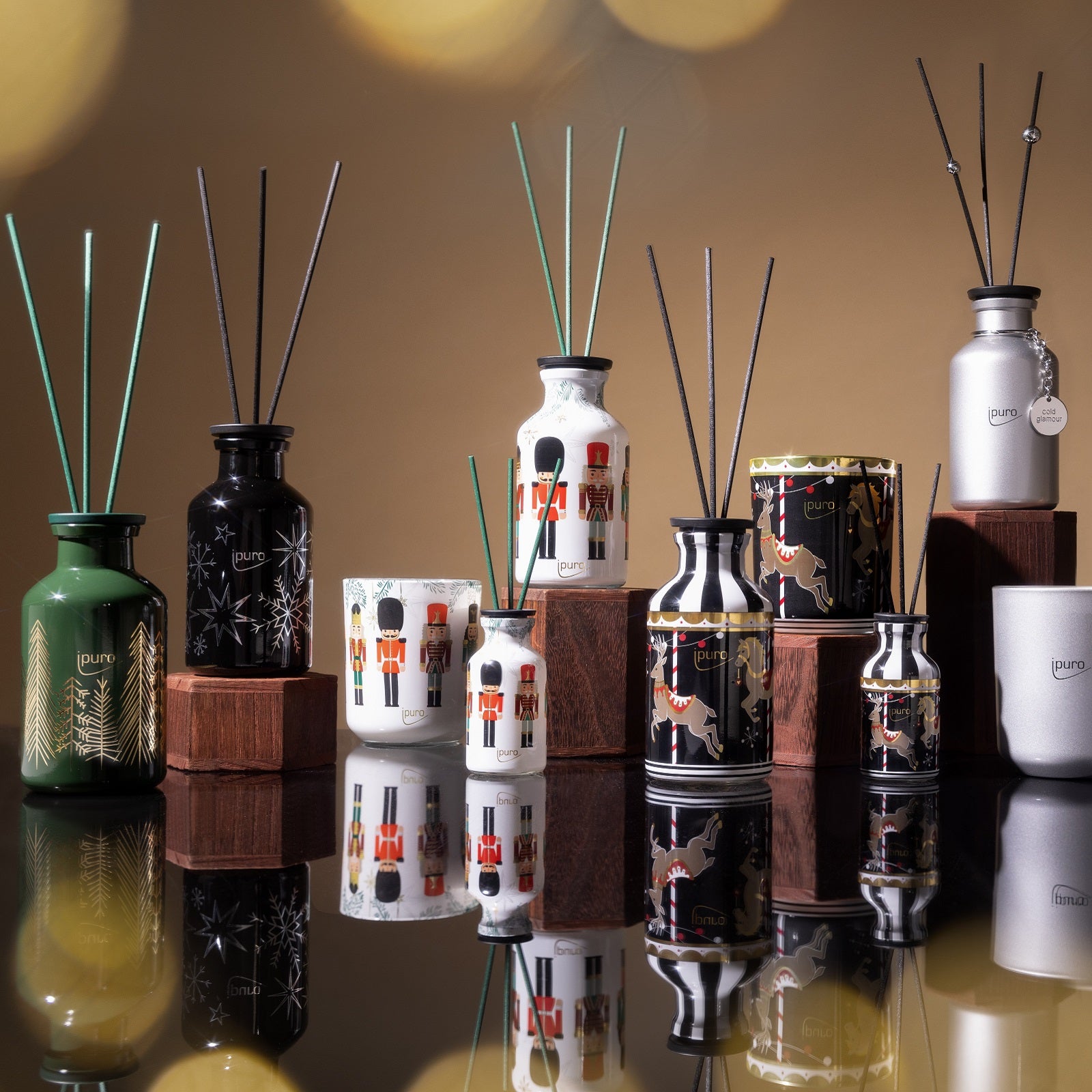 LIMITED EDITION ipuro frozen stardust Raumduft von ipuro wird auf Holzblöcken vor einem warmen, goldenen Hintergrund mit sanften Bokeh-Lichtern präsentiert und verleiht Ihrer Weihnachtsdekoration einen festlichen Touch.