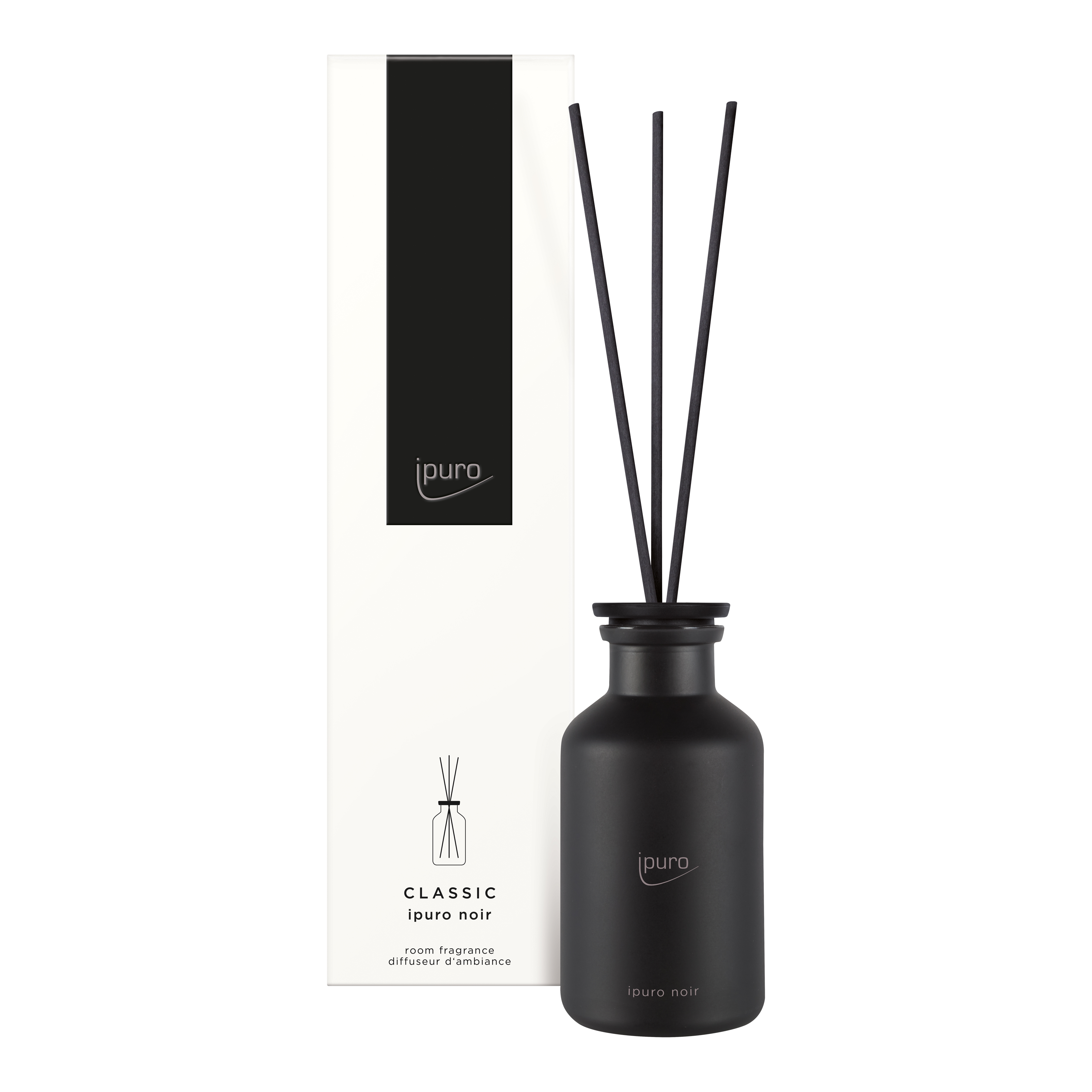 Ein schwarzer Flakon von ipuro CLASSIC ipuro noir Raumduft mit drei Schilfrohren steht neben der hohen, weiß-schwarzen Verpackung mit der Aufschrift "ipuro CLASSIC noir" und den Duftnoten Sandelholz und Rose.