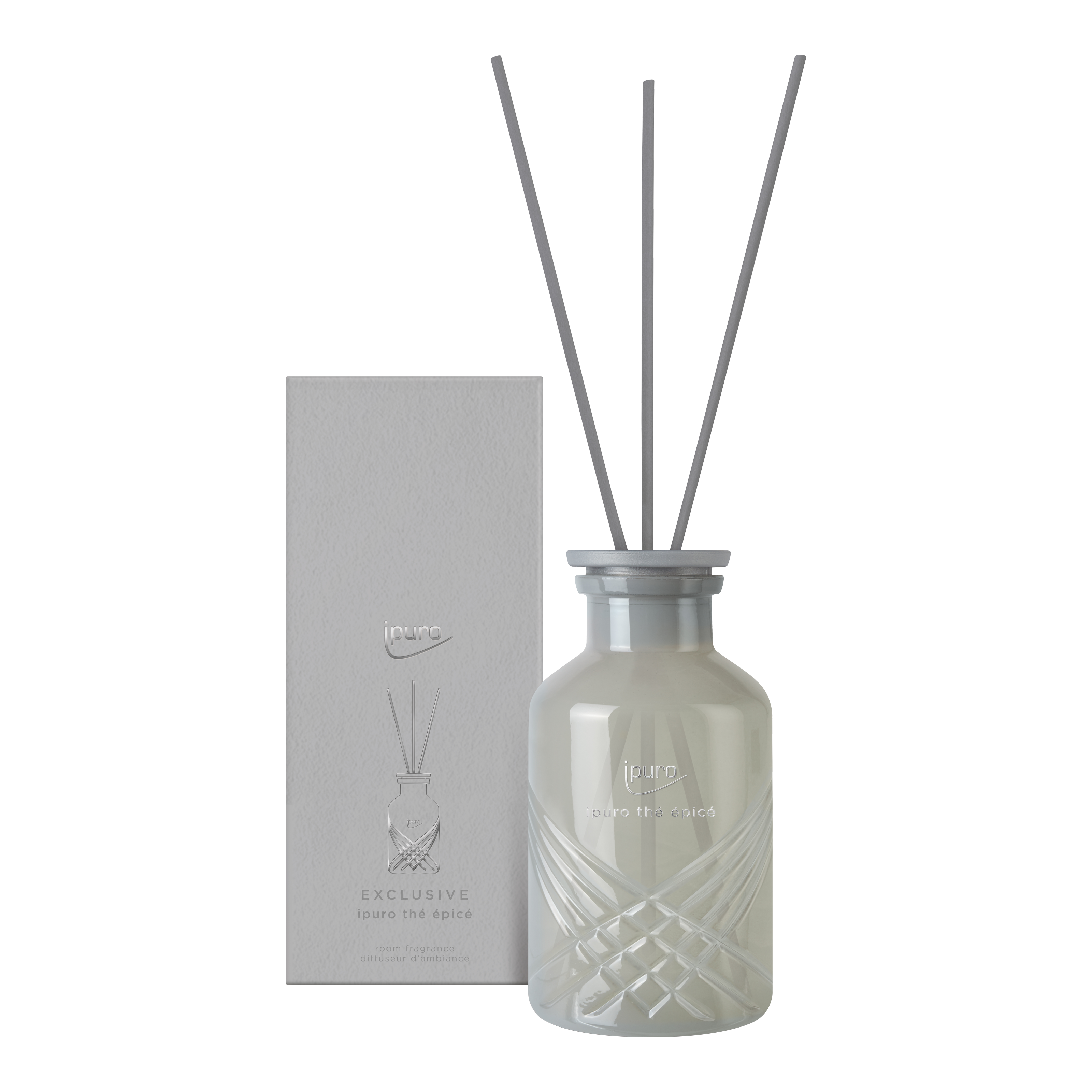 Ein mattierter Glasdiffusor mit drei langen Stäbchen steht neben einer passenden Schachtel, beide mit der Aufschrift ipuro EXCLUSIVE thé epicé. Das subtile Rautenmuster und die Noten von Matcha-Tee und Zitrone verkörpern den eleganten Stil der Marke ipuro.