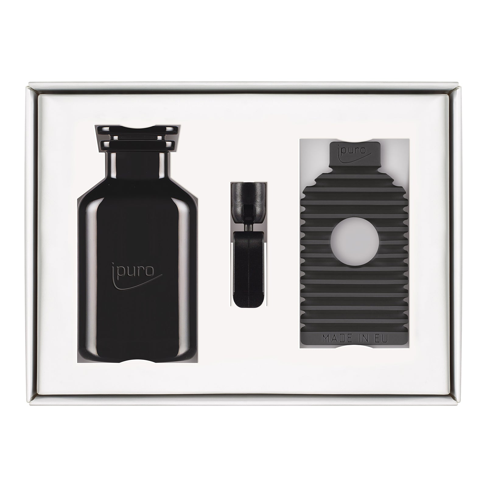 Das CLASSIC ipuro noir Autoduft-Set von ipuro besteht aus einem schwarzen Flakon, einem kleinen Clip und einem gerippten Halter mit kreisrunder Öffnung, der elegante Rose- und Sandelholznoten widerspiegelt, sauber arrangiert vor einem weißen Hintergrund.