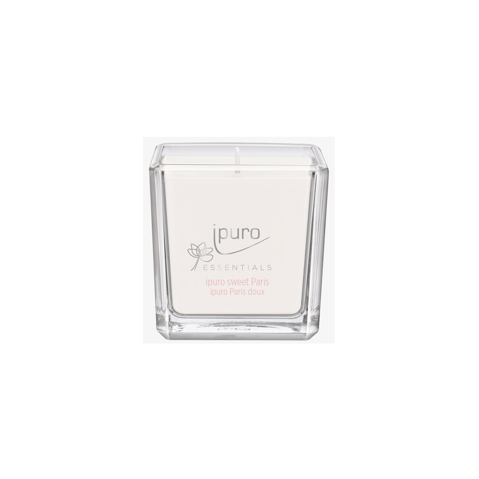 Die ESSENTIALS ipuro sweet paris Duftkerze von ipuro ist eine weiße Kerze in einem klaren, quadratischen Glas mit blumigen Noten von Karamell und Vanille, mit rosa und grauem Text auf dem Etikett.