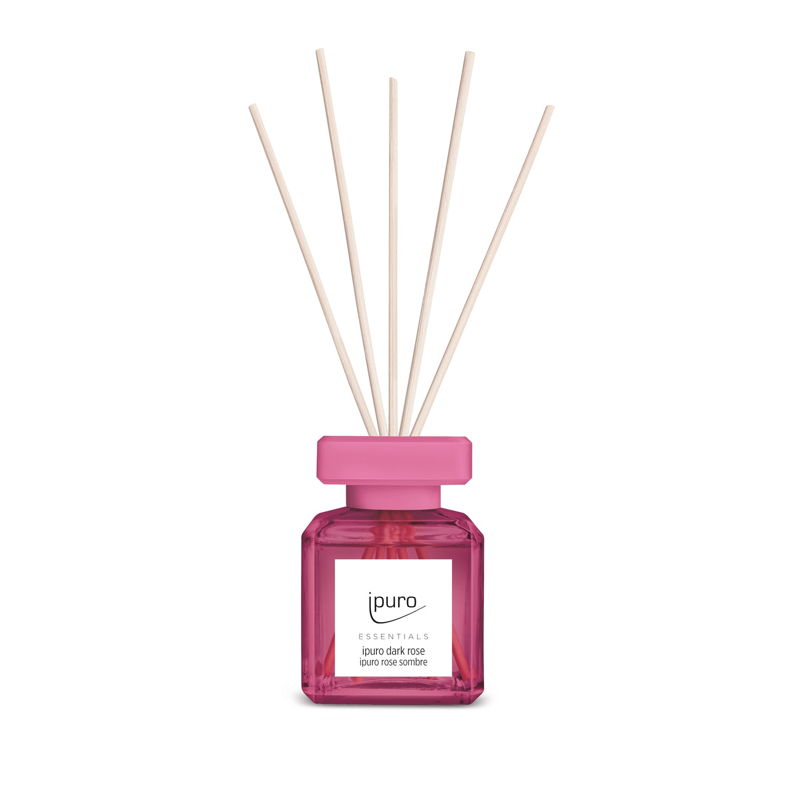 Ein rosafarbener Glasdiffusor mit der Aufschrift "ESSENTIALS ipuro dark rose" von ipuro mit rosafarbener Kappe und fünf Holzblättern verströmt einen blumigen Rosenduft und steht aufrecht auf einem weißen Hintergrund.