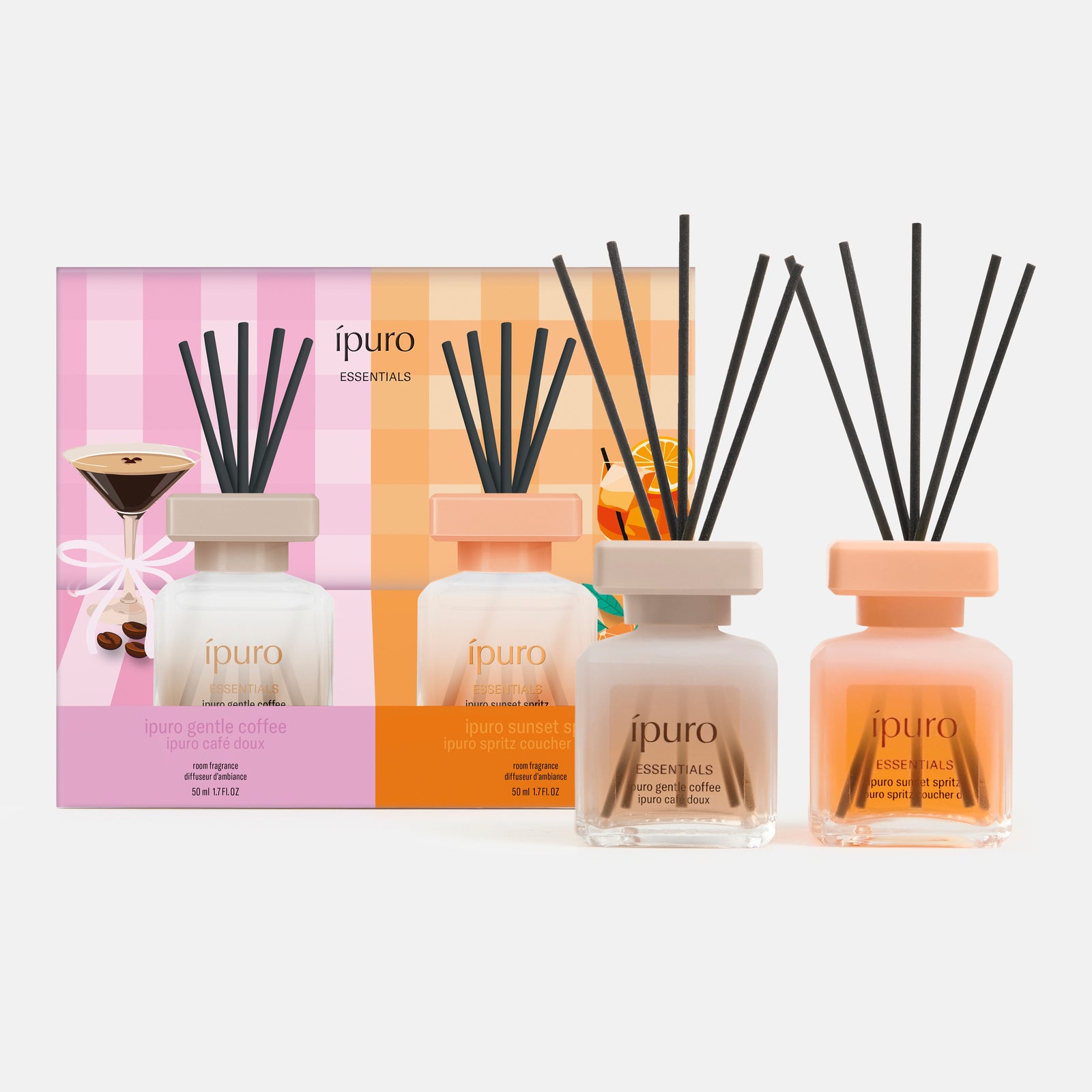 Das ipuro ESSENTIALS sunset spritz & gentle coffee Geschenk-Set besteht aus drei duftenden Rohrdiffusoren in Glasflaschen mit schwarzen Stäbchen, die vor einer farbenfrohen Schachtel mit Kaffee- und Bitterorange-Illustrationen für eine Gourmet-Atmosphäre stehen.