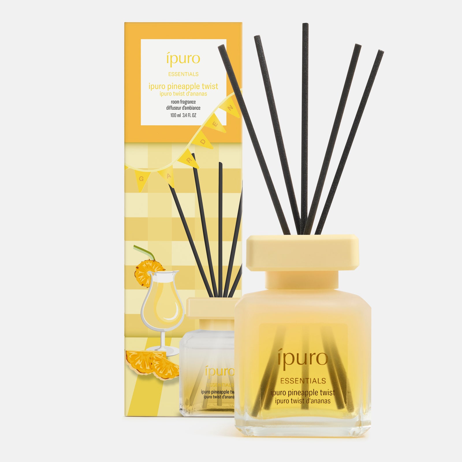 Der gelbe Flakon des ipuro ESSENTIALS Ananas-Twist-Duftzerstäubers mit schwarzem Schilfrohr steht neben seiner farbenfrohen Verpackung, die tropische Motive von Ananas und Kokosnuss zeigt.