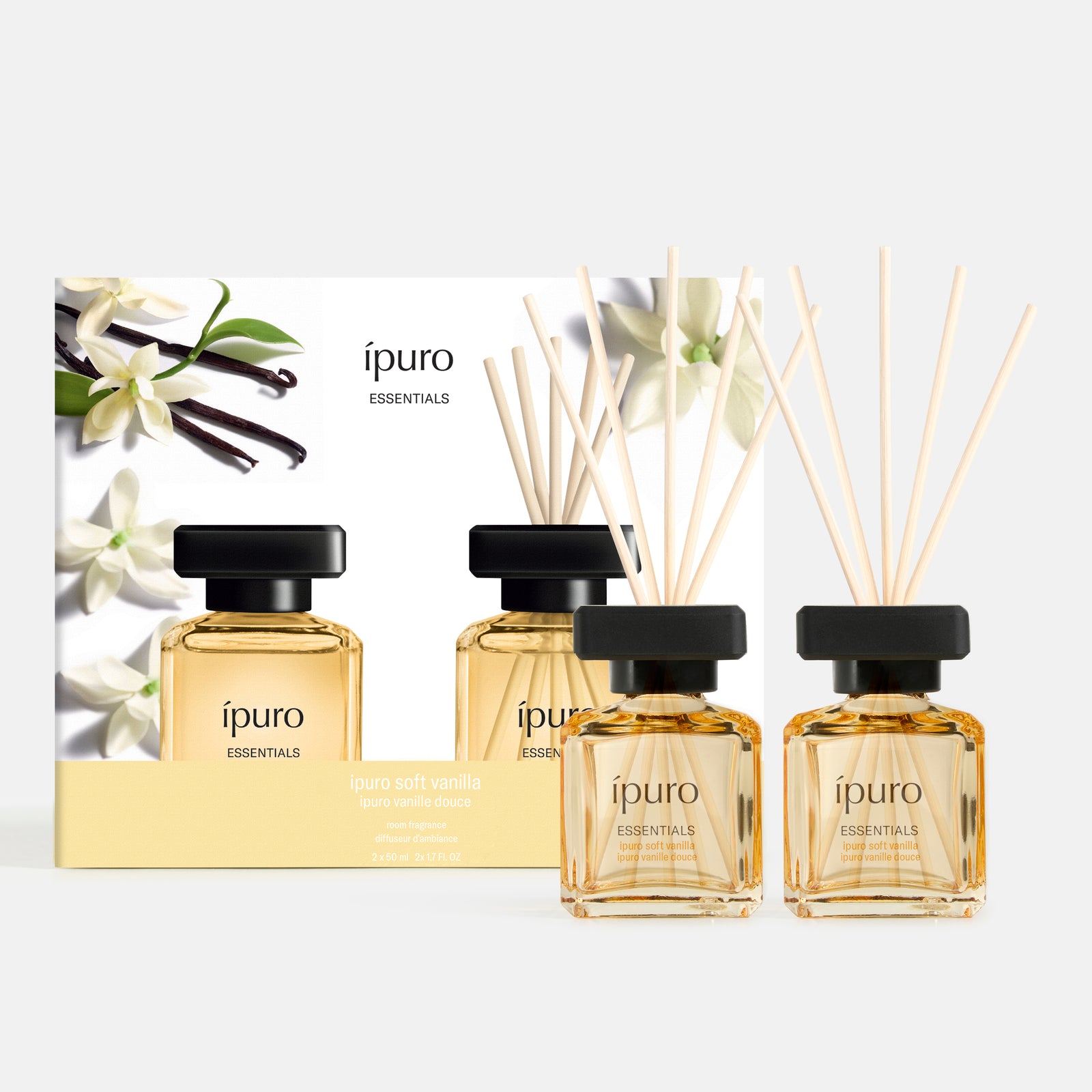 Zwei Glasflaschen ipuro Raumduft-Set ipuro soft vanilla mit Holzstäbchen stehen vor einer passenden Box mit Vanilleblüten und -schoten und erfüllen Ihren Raum mit dem warmen Duft von Vanillenoten.