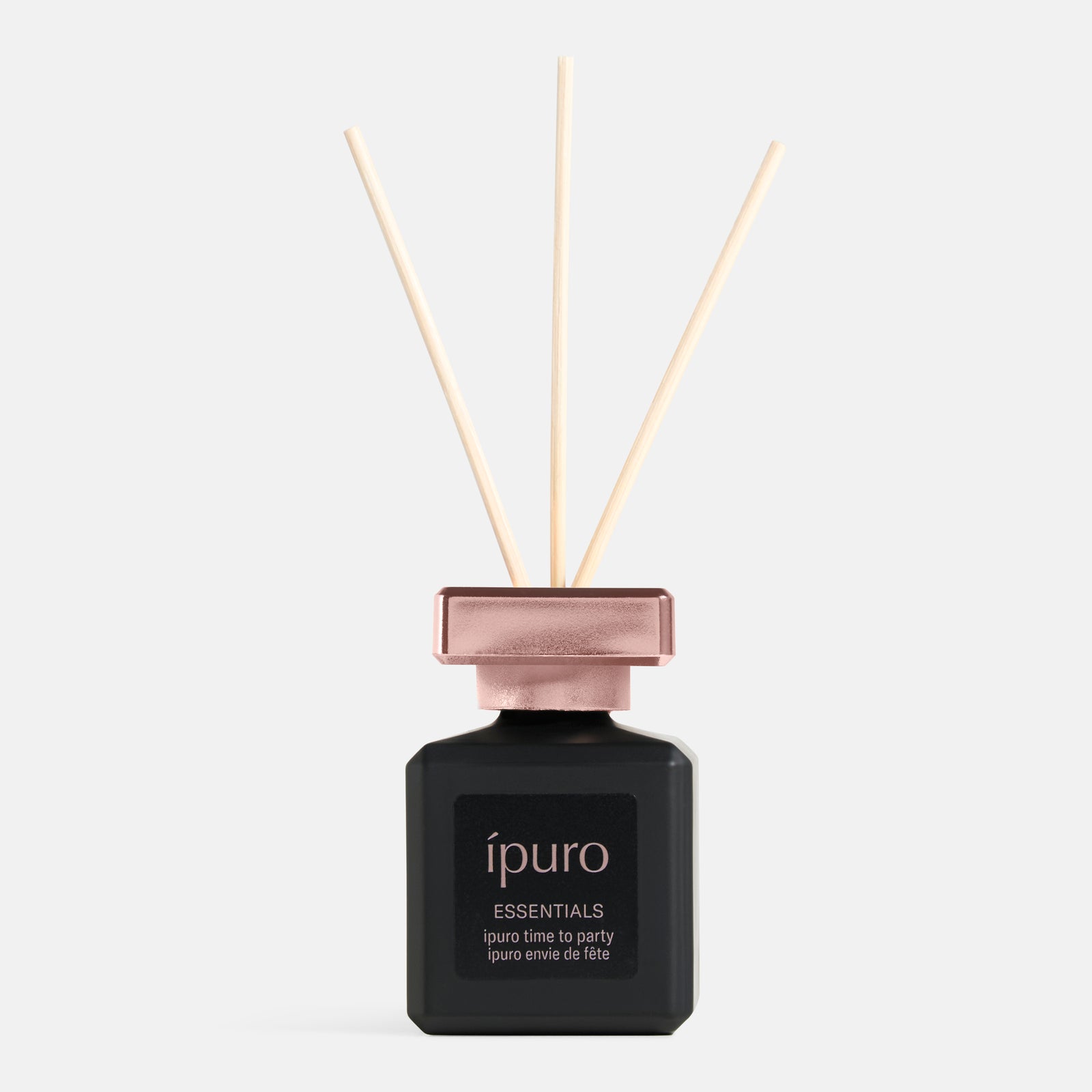 Eine schwarze Flasche ipuro Raumduft "time to party" von ipuro mit roségoldener Metallkappe und drei Holzstäbchen vor einem schlichten, hellen Hintergrund.