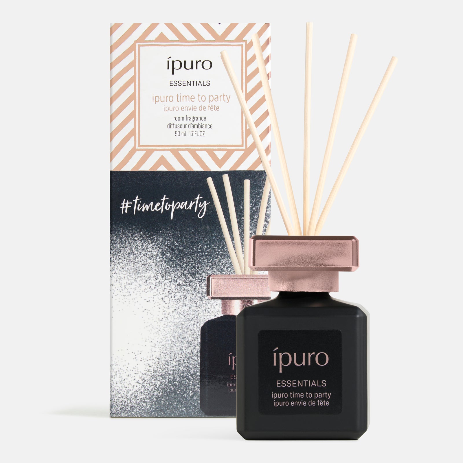 Ein schwarzer und roségoldener ipuro Raumduft "time to party" Diffusor mit hellen Holzblättern steht vor seiner passenden Box, beide von ipuro.