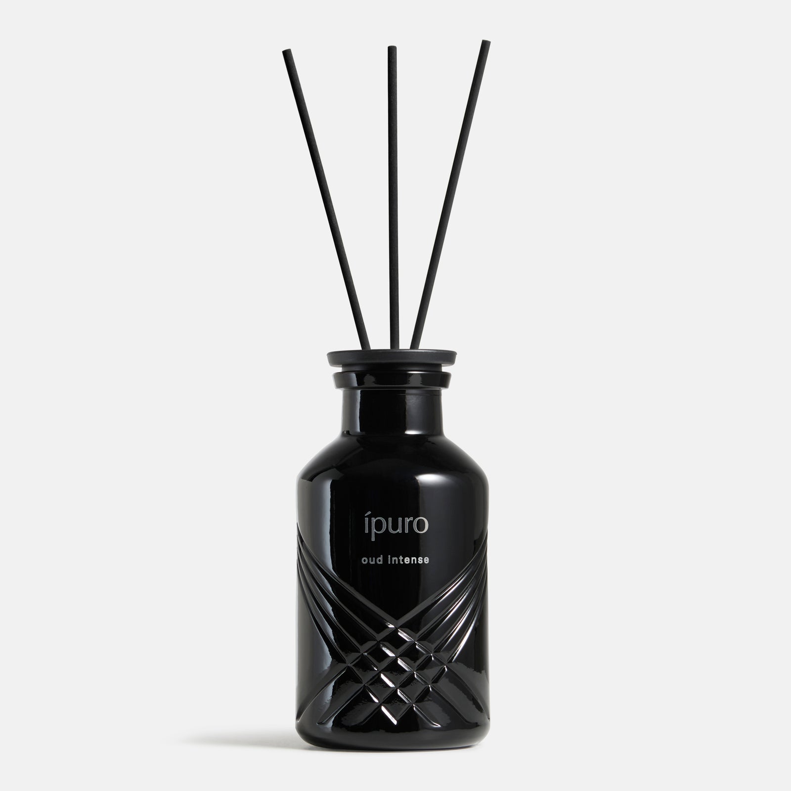 Ein eleganter schwarzer Glasflakon mit der Aufschrift "Raumduft ipuro oud intense" von ipuro enthält schwarze Schilfrohr-Diffusorstäbchen, die ein reichhaltiges Oud- und Safran-Aroma verströmen und vor einem schlichten hellgrauen Hintergrund stehen.