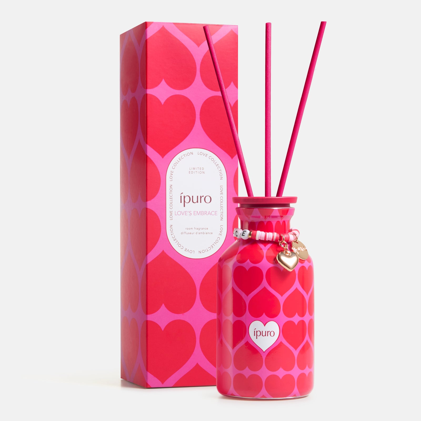 Die LIMITED EDITION ipuro love's embrace Raumduft 240ml von ipuro präsentiert sich in einem rosafarbenen Flakon mit roten Herzmustern, rosafarbenen Stäbchen und Herzanhängern neben der passenden Box. Der Duft enthält Noten von Moschus (Moschus) und Sandelholz (Sandelholz).