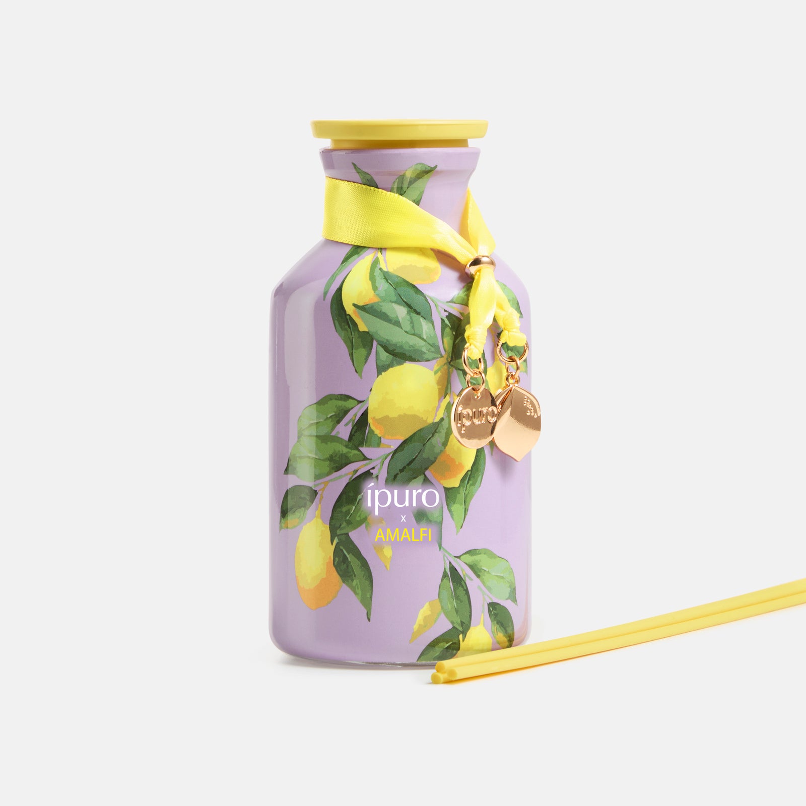 Der LIMITED EDITION ipuro x AMALFI Raumduft 240ml von ipuro besteht aus einem lila Flakon mit aufgemalten gelben Zitronen, grünen Blättern, einer gelben Kappe, einem Band mit goldenen Anhängern und passenden Diffusorstäbchen - und fängt einen blumig-fruchtigen Duft ein.