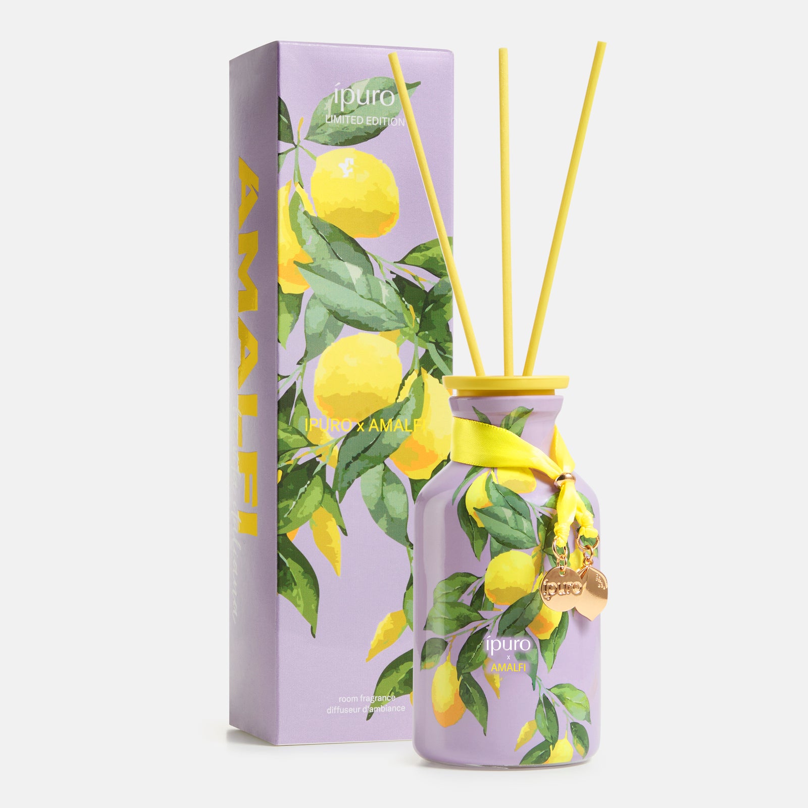 Der LIMITED EDITION ipuro x AMALFI Raumduft 240ml besteht aus einem violetten Diffusor mit gelbem Schilf, Zitronenillustrationen und einem gelben Band. Das Etikett trägt die Aufschrift ipuro Amalfi Limited Edition und wird mit einer passenden, mit Zitronen und Blättern verzierten Schachtel geliefert.