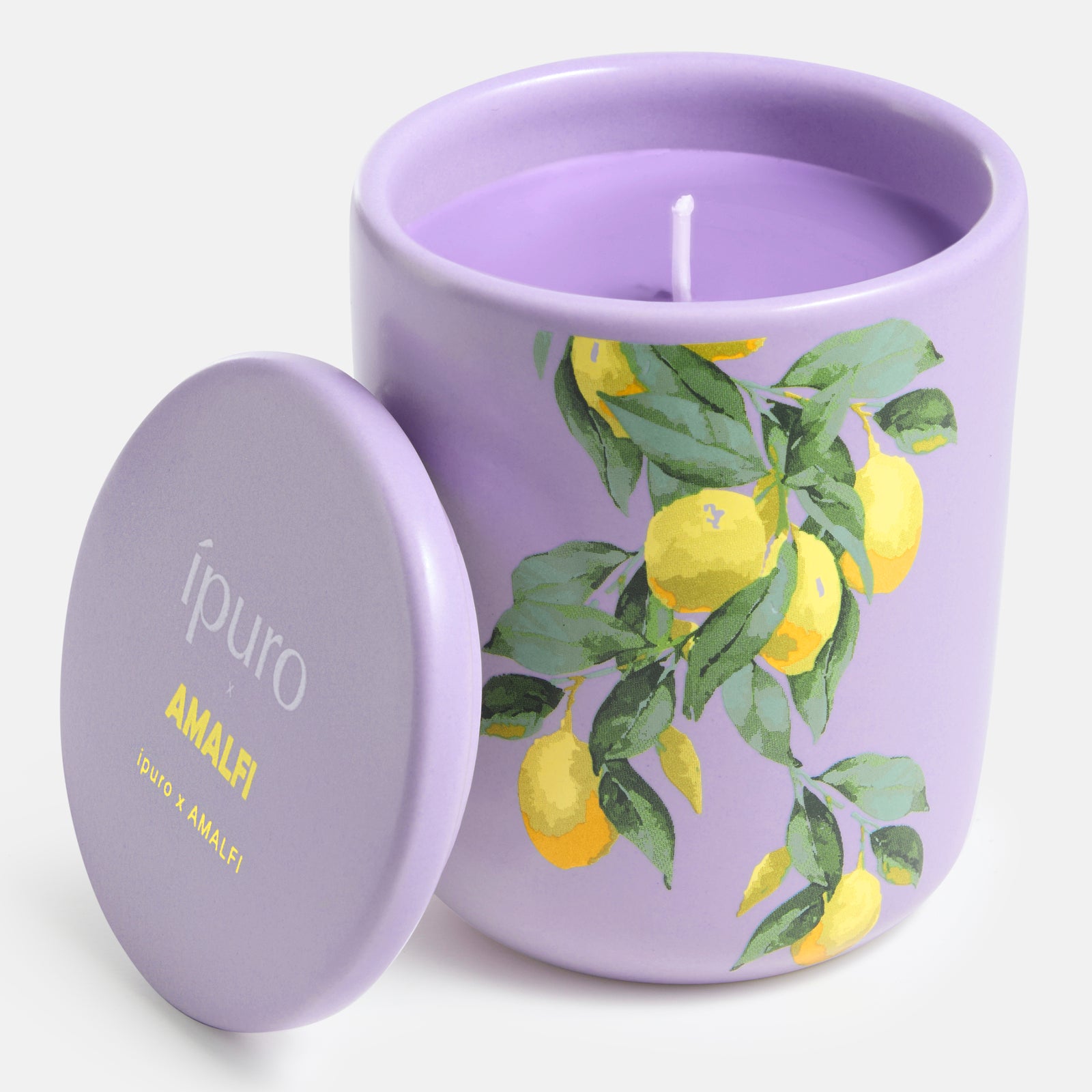 Die Duftkerze ipuro x Amalfi 270g von ipuro wird in einem lavendelfarbenen Gefäß mit passendem Deckel geliefert, der mit gelben Zitronen und grünen Blättern bemalt ist. Auf dem Deckel steht ípuro AMALFI", ein Hinweis auf den blumigen Zitrusduft von Amalfi. Ein zentraler Docht ist sichtbar.