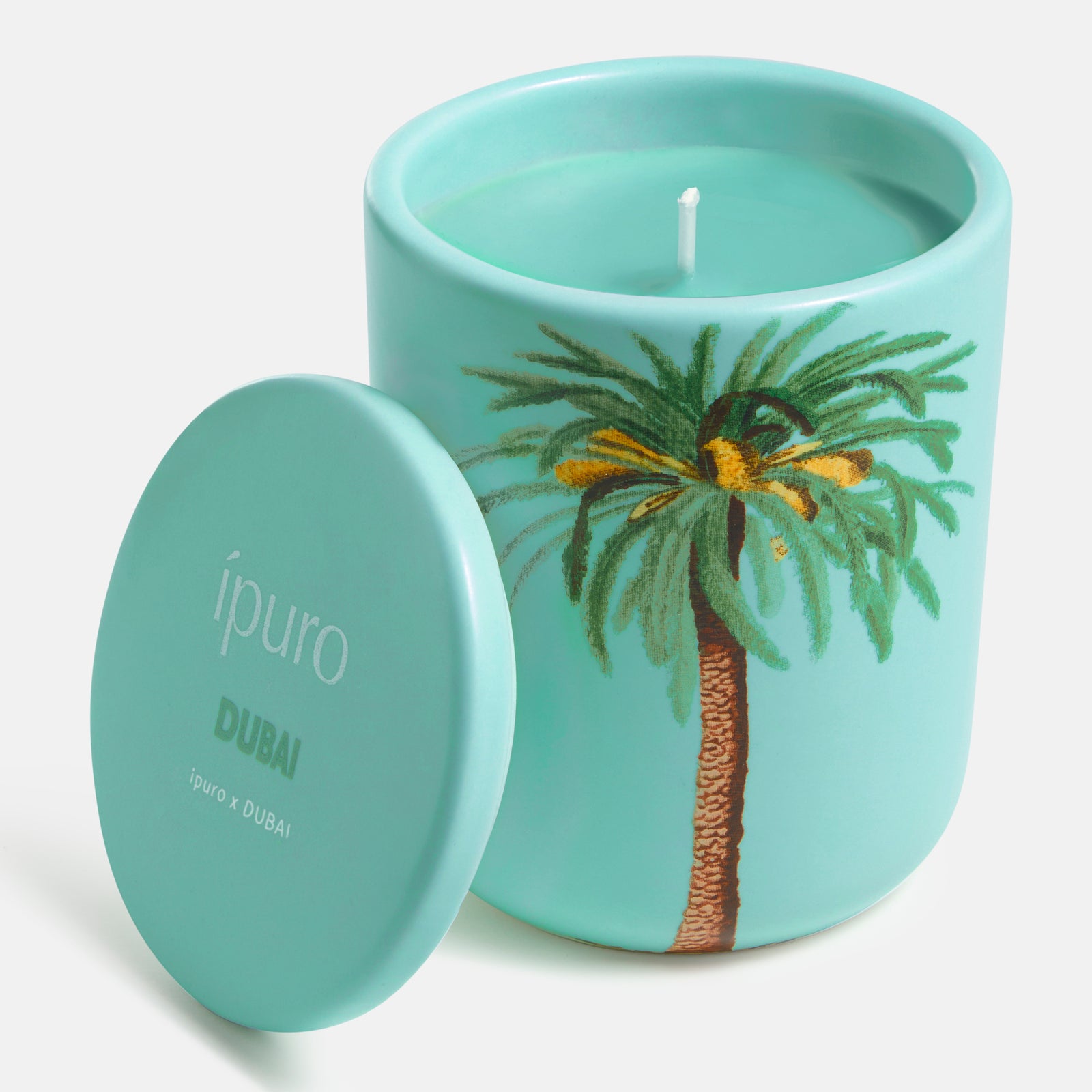Die ipuro Duftkerze ipuro x Dubai 270g besteht aus einem türkisfarbenen Glas mit einer Palme und dem Schriftzug ipuro" auf dem Deckel. Die nicht angezündete Kerze verströmt Sandelholznoten, die von orientalischen Parfüms inspiriert sind und die Essenz von Dubai einfangen.