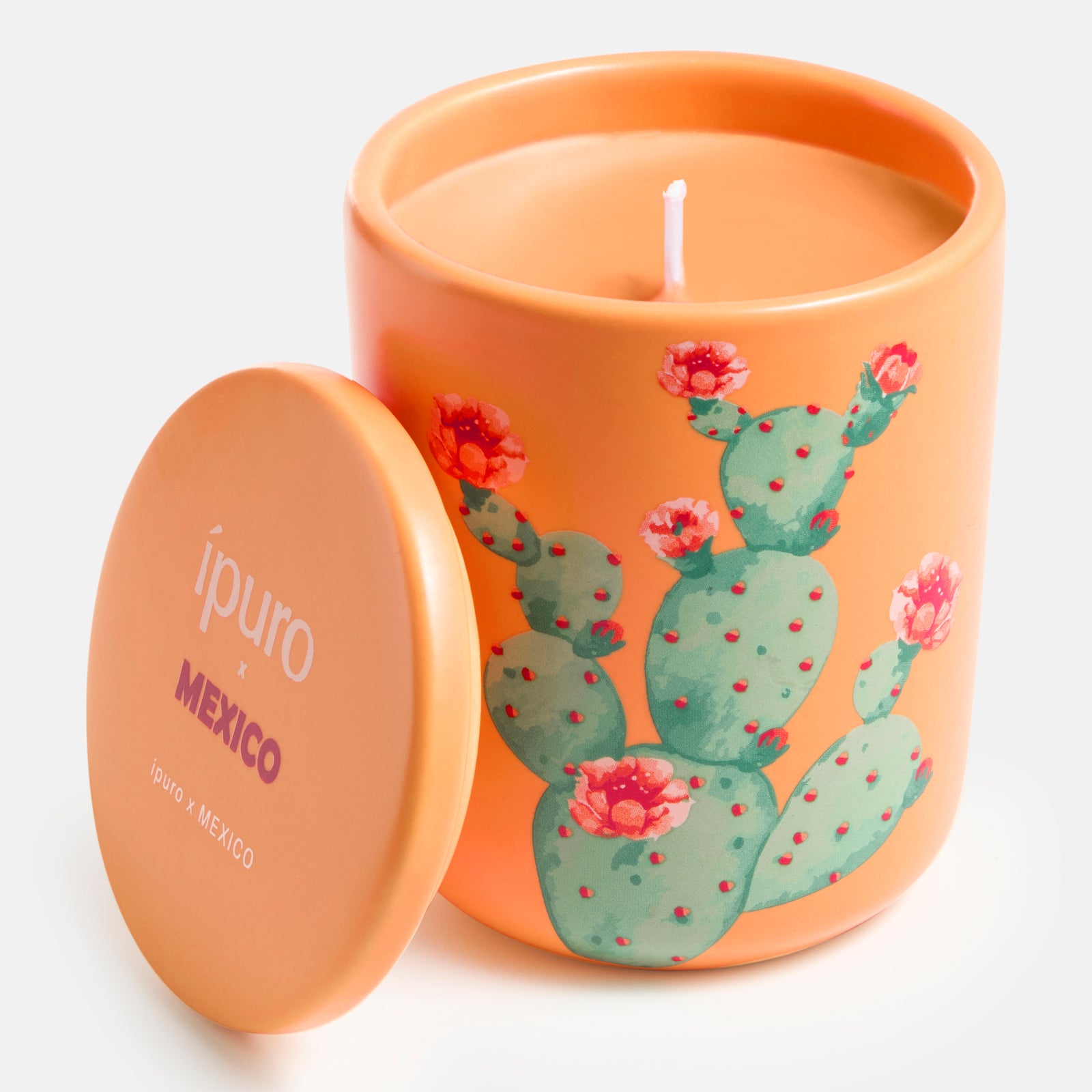 Die Duftkerze ipuro x Mexico 270g von ipuro ist eine orangefarbene Kerze mit Deckel, die einen Kaktus mit rosa Blüten zeigt. Ihr Duft Mandarine & Kaktusfeige fängt den Duft Mexiko ein. Auf dem Deckel steht "ipuro x MEXICO".
