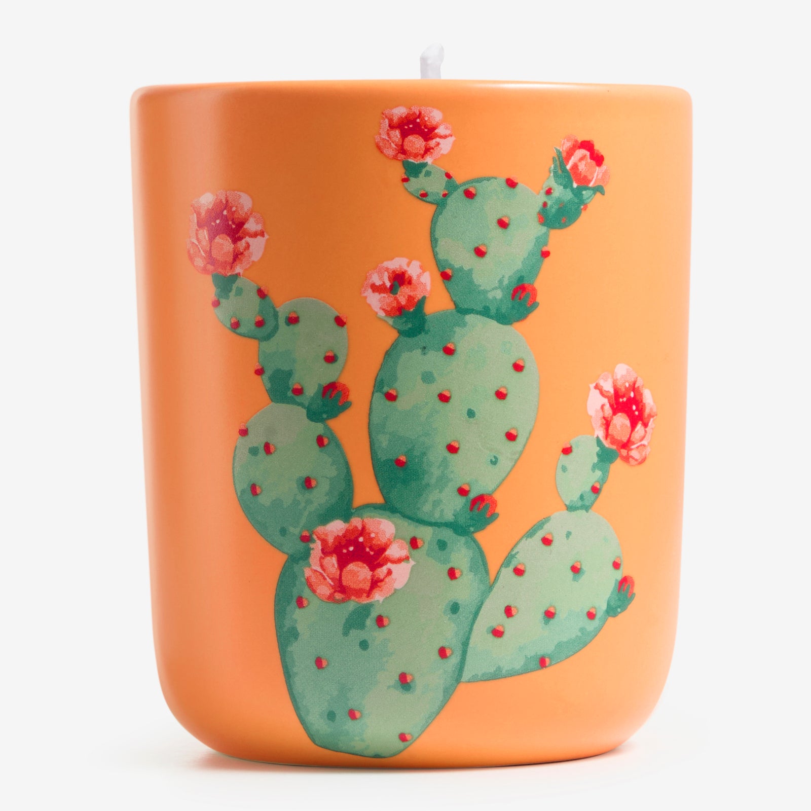 Die ipuro Duftkerze x Mexico 270g zeigt einen leuchtend orangefarbenen Halter mit einer grünen Kaktusfeige und blühenden rot-rosa Blumen vor einem schlichten weißen Hintergrund. Der kräftige mandarinefarbene Farbton ist von der Essenz von Duft Mexiko inspiriert.