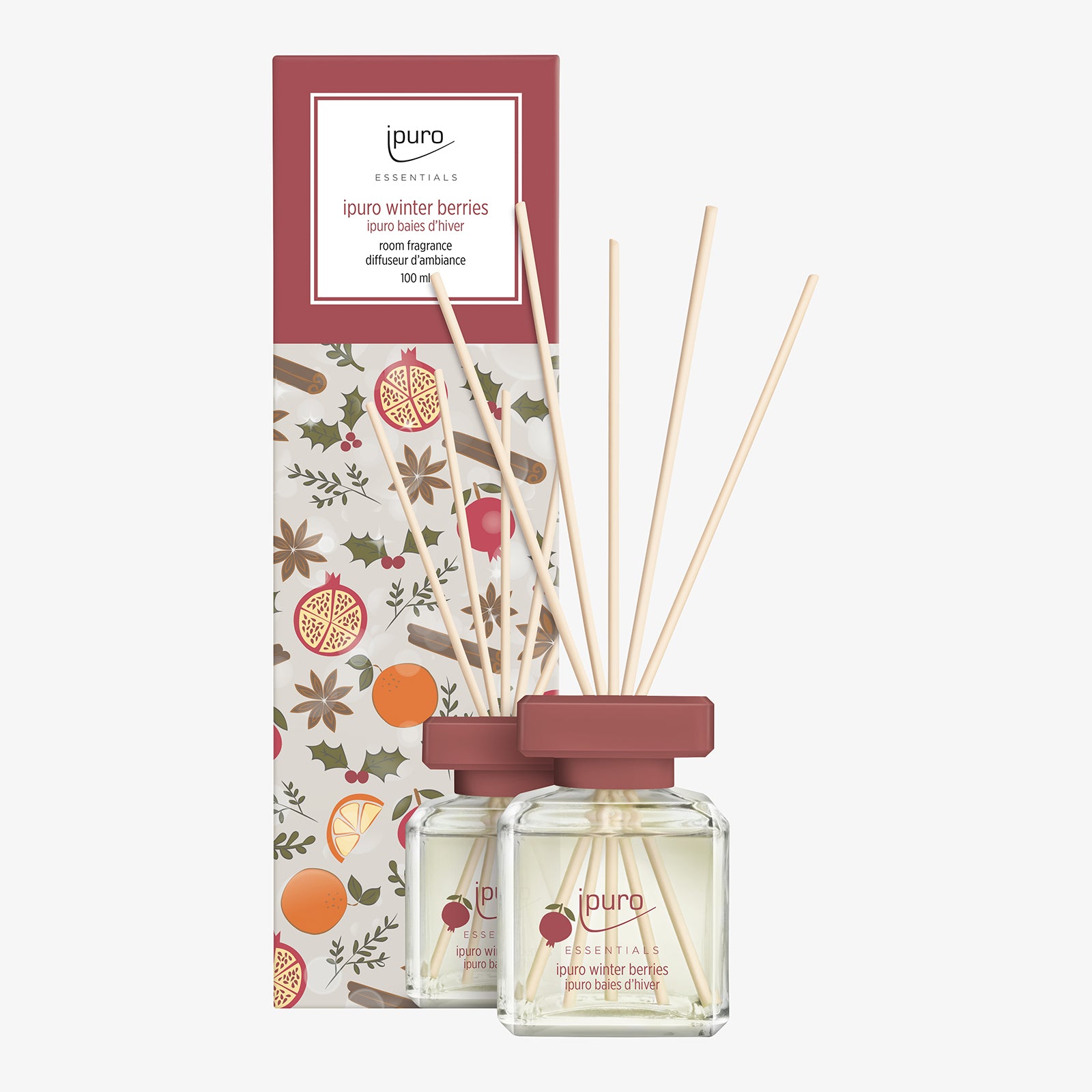Der Duftzerstäuber ipuro ESSENTIALS Raumduft Winter Berries besteht aus einem Glasflakon mit Holzschilf und wird in einer dekorativen Verpackung mit Abbildungen von Beerennoten, Orangenscheiben, Granatapfel und Blättern geliefert.