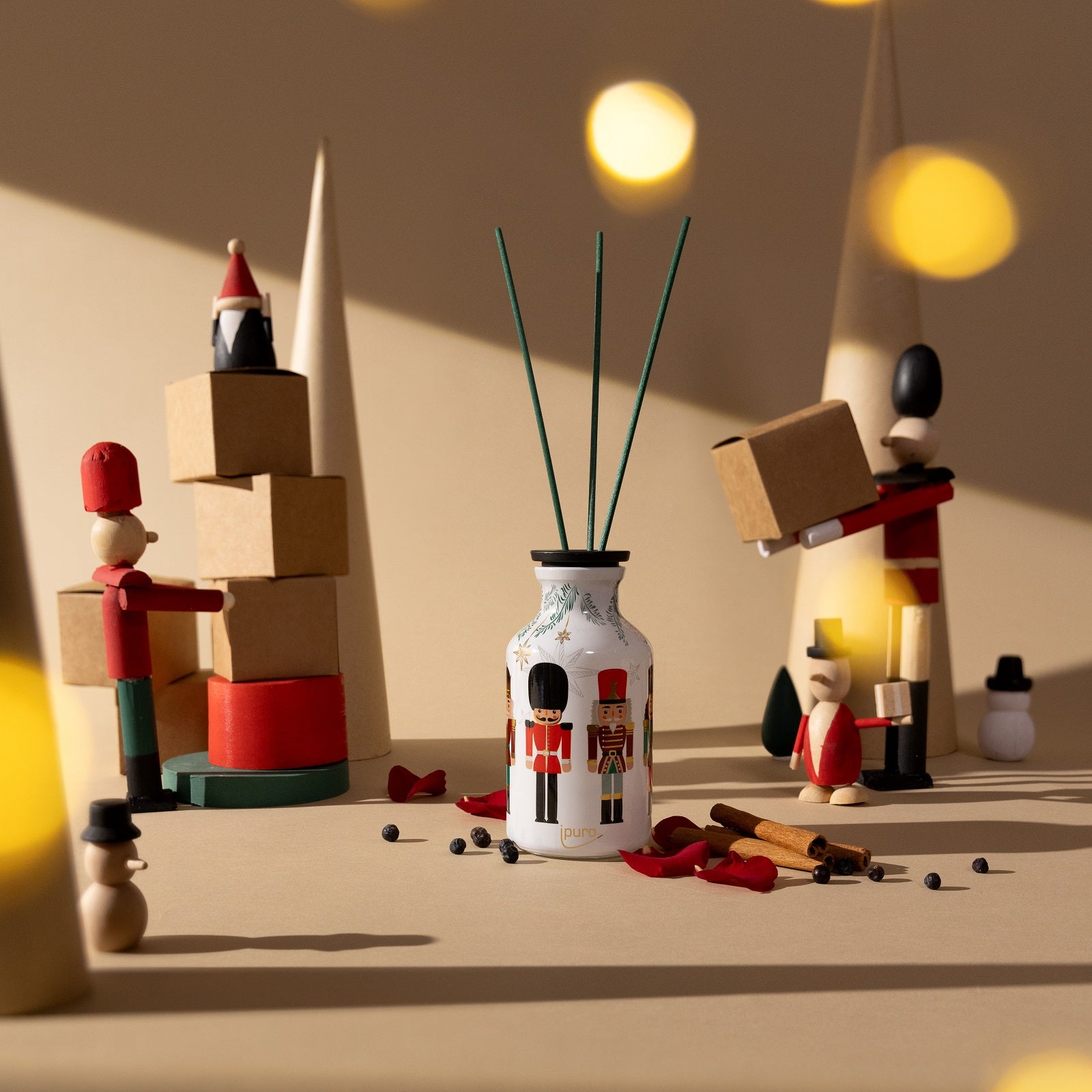 Schaffen Sie ein festliches Ambiente mit hölzernen Spielzeugsoldaten, gestapelten Kisten und dem Raumduft-Diffusor LIMITED EDITION ipuro finest season von ipuro - mit Noten von Zedernholz, Zimtstangen, Rosenblättern und Pfefferkörnern vor einem beigen Hintergrund.
