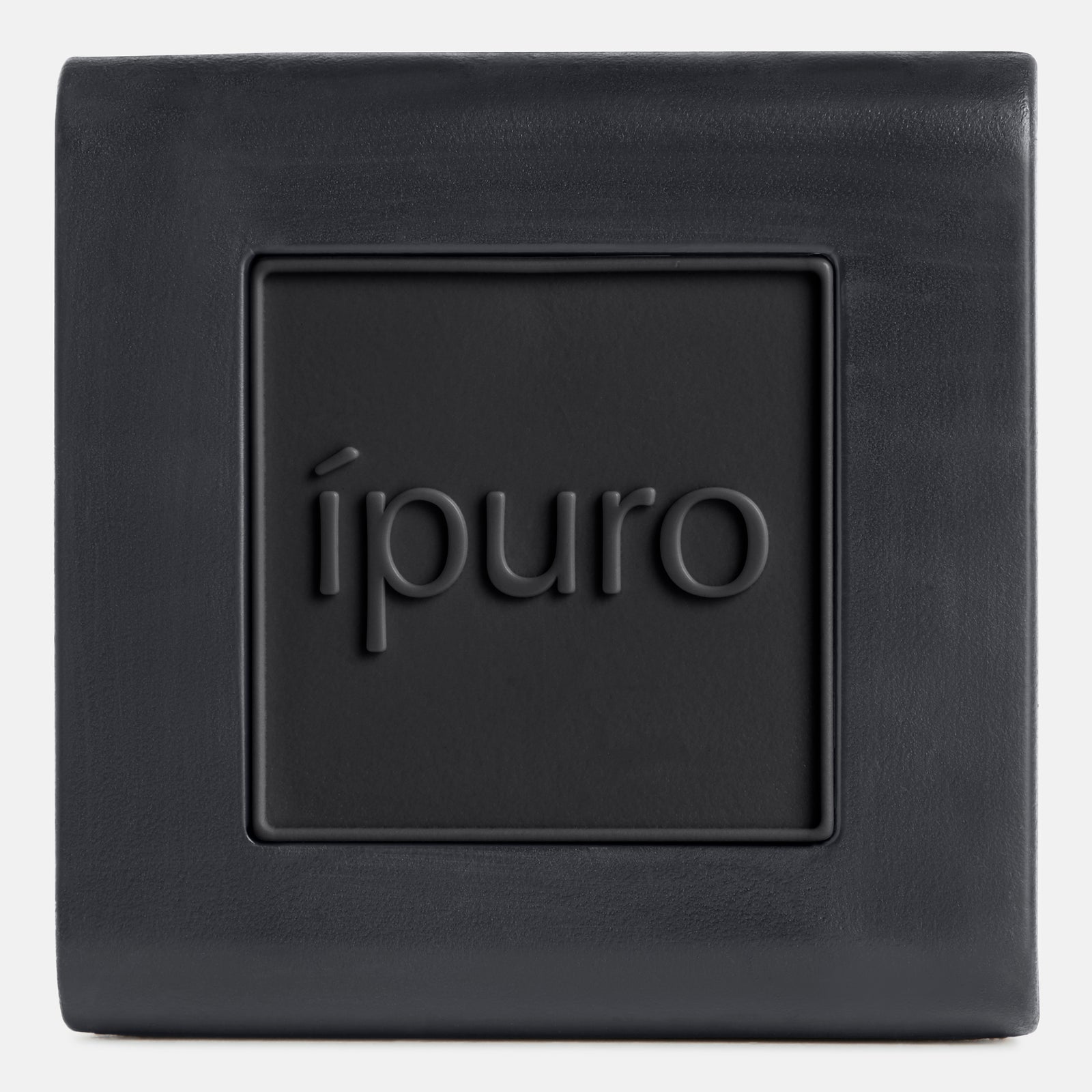 Auf der quadratischen, dunkelgrauen Autoduft ipuro black bamboo von ipuro ist in der Mitte in Kleinbuchstaben "ipuro" eingeprägt. Sein minimalistisches Design mit glatten Oberflächen und einer vertieften Platte erinnert an grüne Frische und eine moderne, frische Ästhetik.