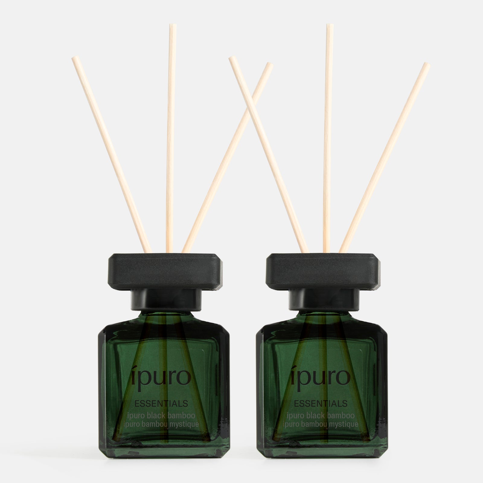 Zwei grüne Glasflaschen mit der Aufschrift ipuro Raumduft-Set black bamboo und schwarzem Deckel, die jeweils vier natürliche Schilfrohrstäbchen enthalten, stehen nebeneinander und erfüllen jeden Raum mit dem frischen, kräuterigen Bambusduft von ipuro.