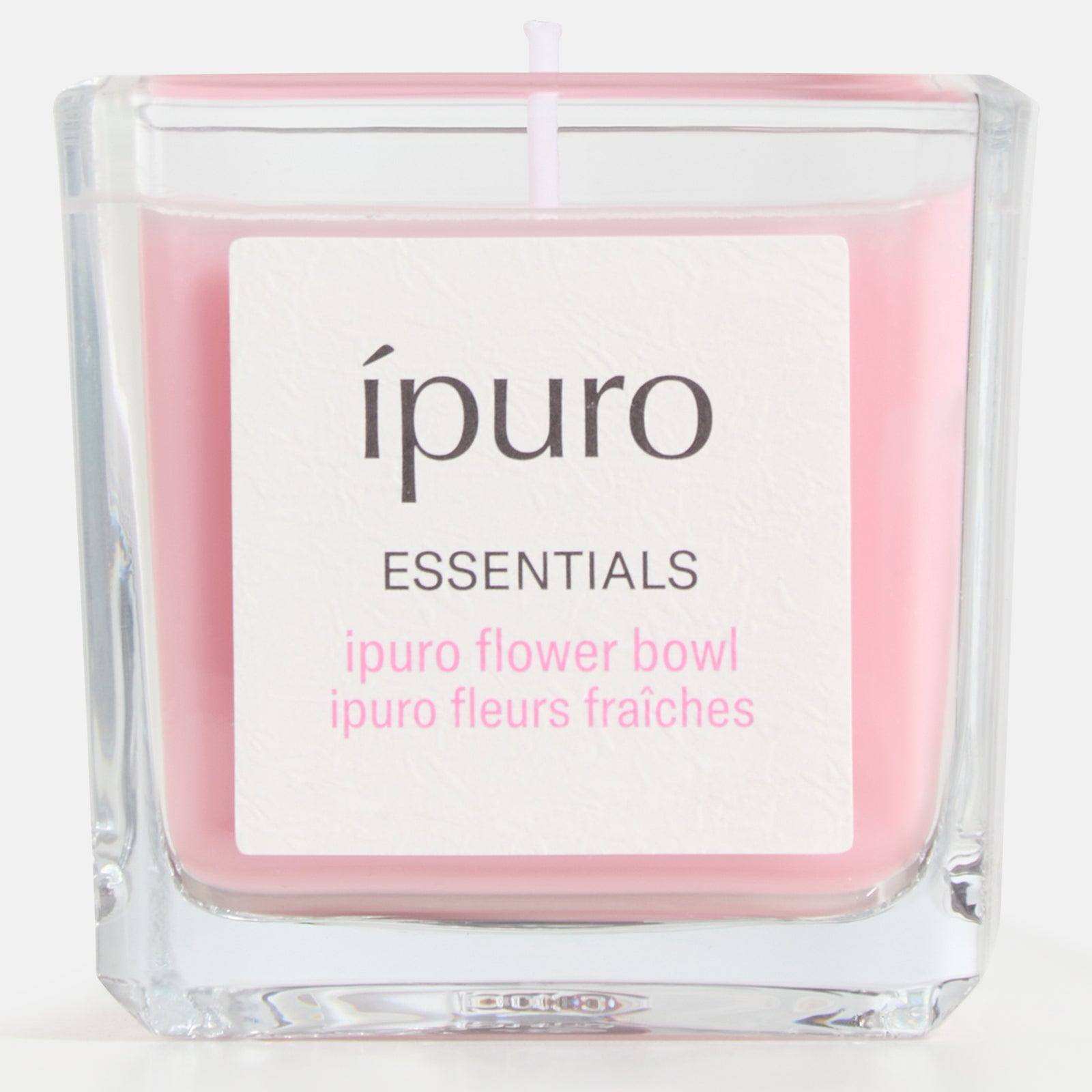 Die Duftkerze ipuro flower bowl von ipuro ist eine rosafarbene Kerze in einem klaren, quadratischen Glasbehälter, die ein blumiges, sommerliches Flair und belebende Frische in jeden Raum bringt.