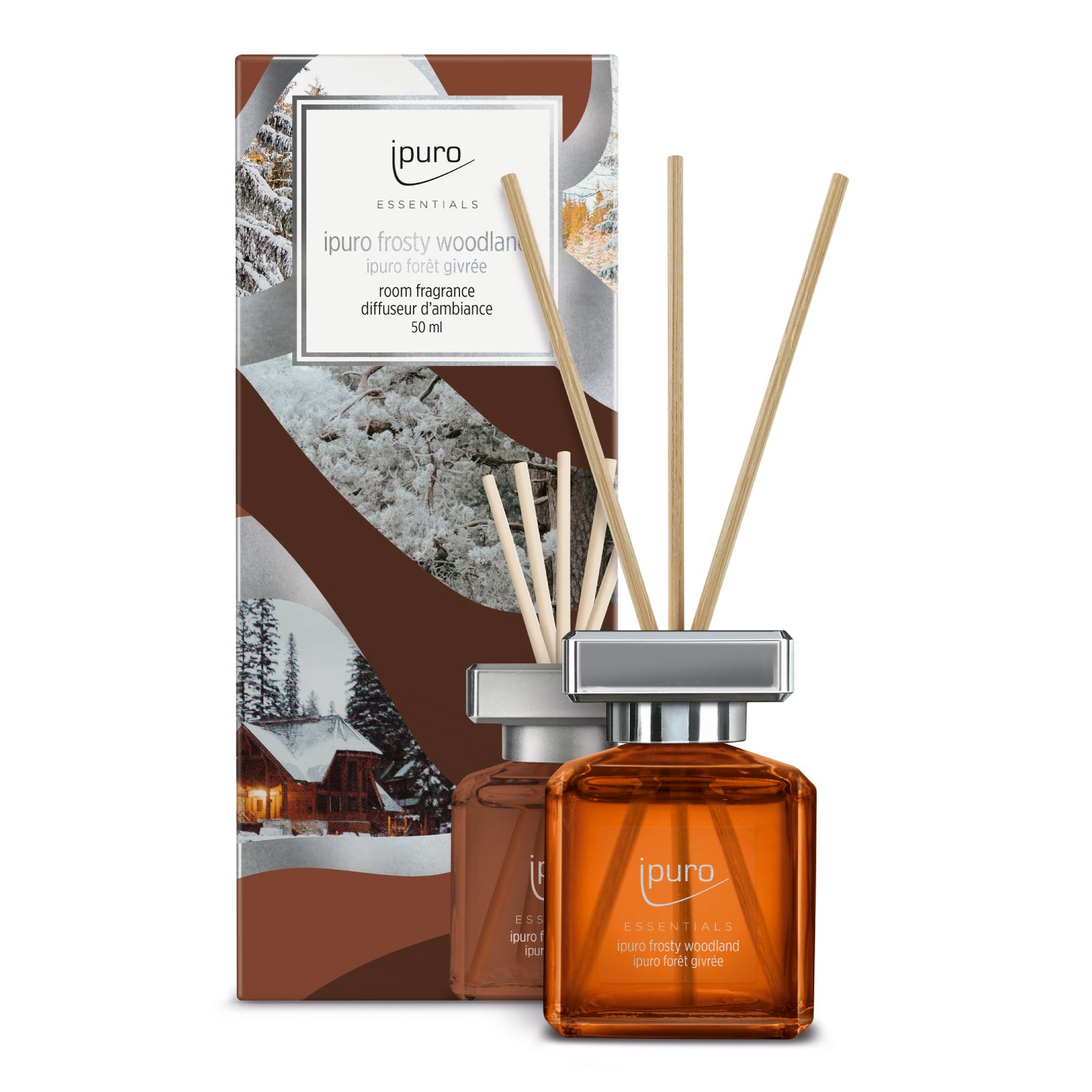 Braunglas-Diffusorflasche mit Schilfrohrstäbchen mit der Aufschrift ipuro Essentials frosty woodland neben der Schachtel, die eine verschneite Hütten-Winterszene und das ipuro-Branding zeigt.