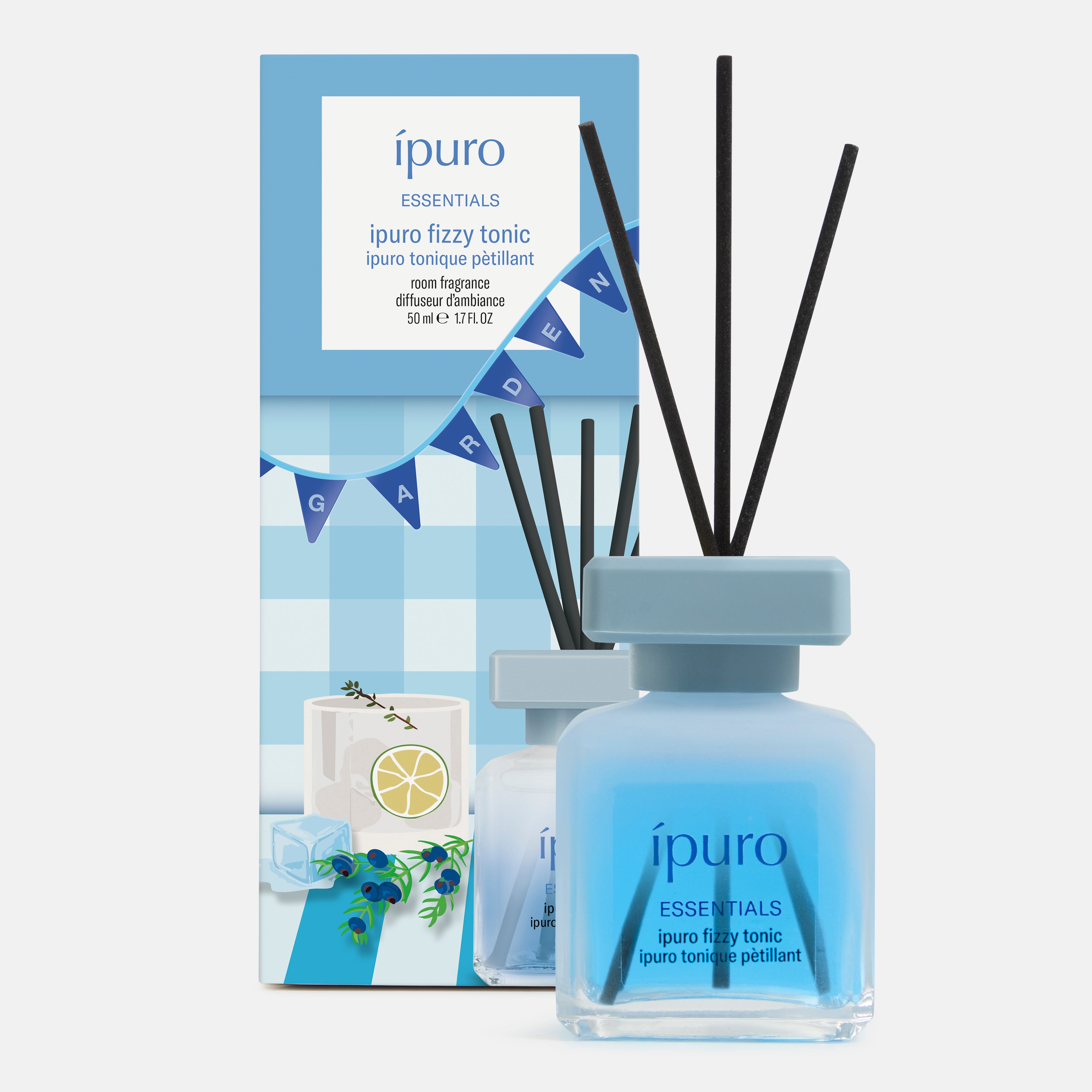 Eine blaue Flasche des ESSENTIALS ipuro fizzy tonic reed diffuser von ipuro mit schwarzen Stäbchen steht vor einer blau-weißen Schachtel, die mit Zitronen, blauen Blumen und einem GARDEN-Banner verziert ist, was auf einen erfrischenden Gin-Duft schließen lässt.