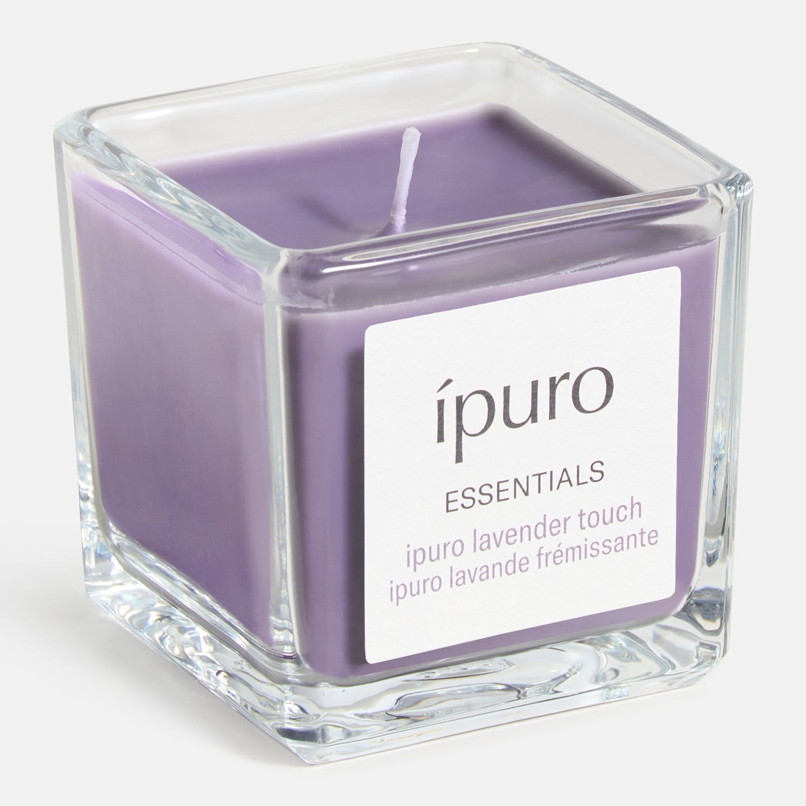 Die ipuro Duftkerze lavender touch ist eine quadratische Glaskerze mit violettem Wachs und einem einzelnen Docht. Genießen Sie wohltuende Lavendel- und frische Noten für eine beruhigende Atmosphäre. Auf dem Etikett steht "ipuro ESSENTIALS" und "ipuro lavande frémissante".