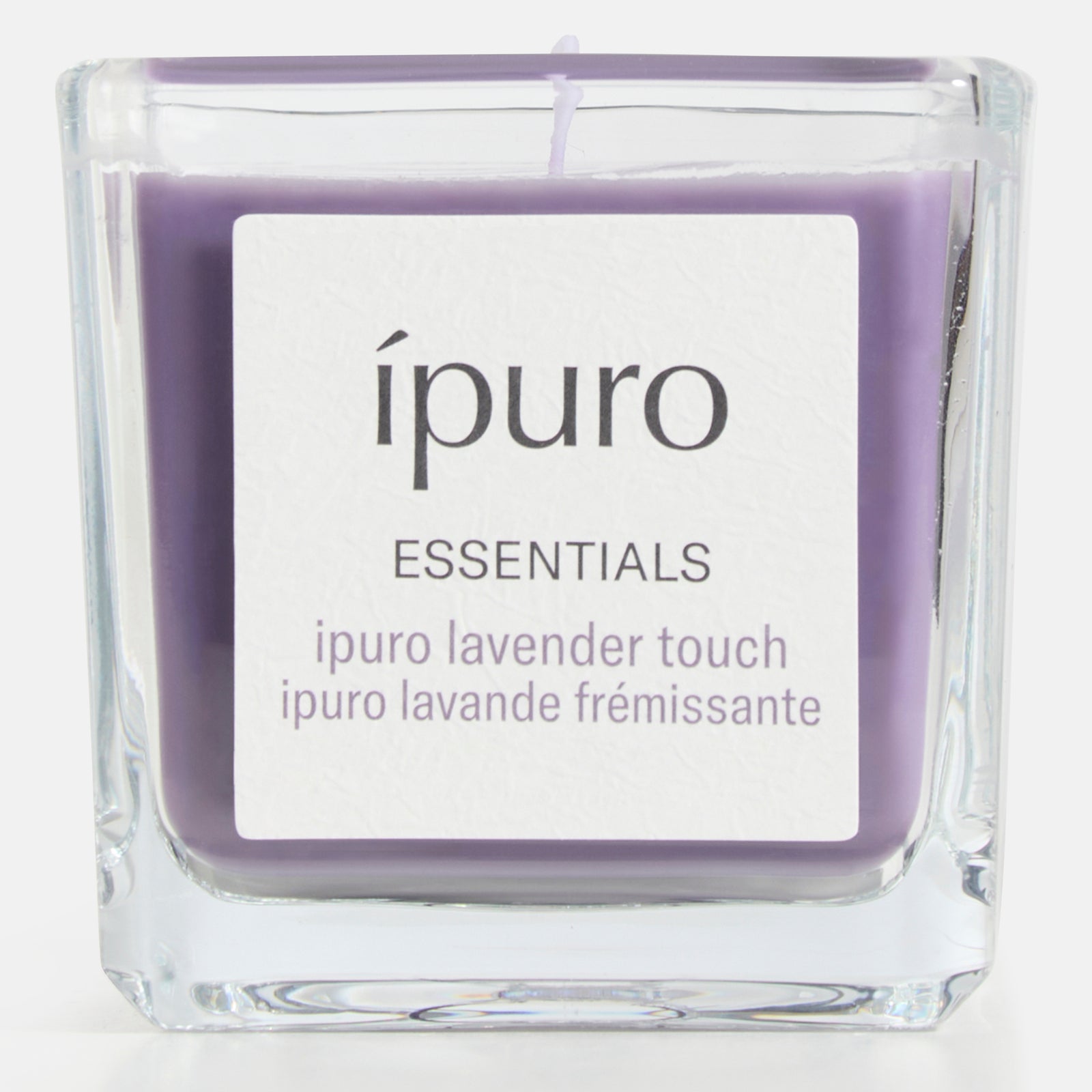 Die ipuro Duftkerze lavender touch ist eine quadratische Glaskerze mit lila Wachs und Lavendelduft, mit dem Etikett: ípuro ESSENTIALS, ipuro lavender touch, lavande frémissante-Lavendel gemischt mit frischen Noten für ein erfrischendes Aroma.