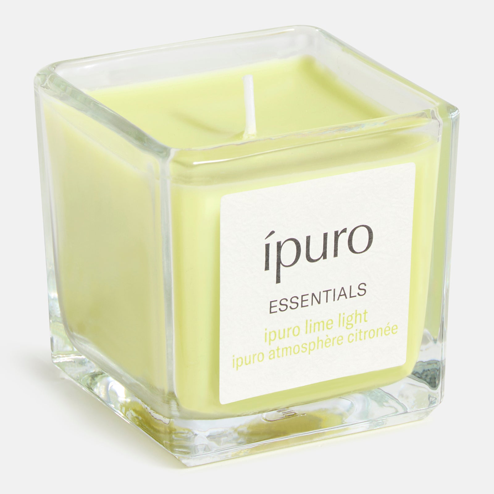Die hellgrüne Duftkerze ipuro lime light von ipuro in einem klaren, quadratischen Glas mit weißem Etikett verströmt reinen Duft und den erfrischenden Duft von Zitronengras.