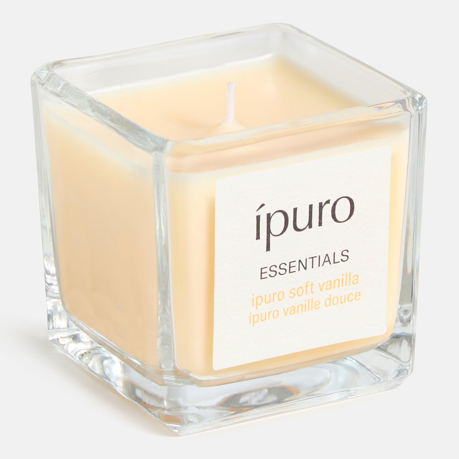 Ein quadratischer Glasbehälter mit einer beigen "Duftkerze ipuro soft vanilla" von ipuro mit der Aufschrift "ipuro soft vanilla", die warme Vanillenoten auf weißem Hintergrund zeigt.