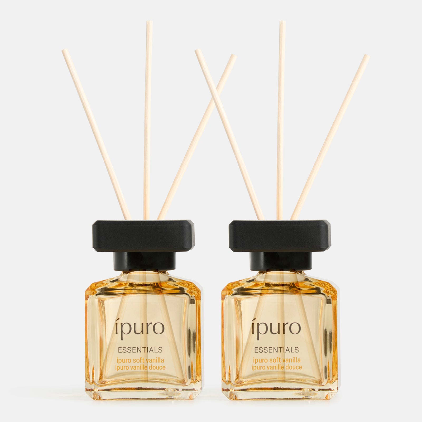 Zwei identische ipuro Raumduft-Set Soft-Vanille-Diffusoren, jeweils mit schwarzer Kappe und vier Holzblättern, die zarte Vanillenoten und Sandelholz hervorheben, werden nebeneinander auf weißem Hintergrund ausgestellt. Marke: ipuro.