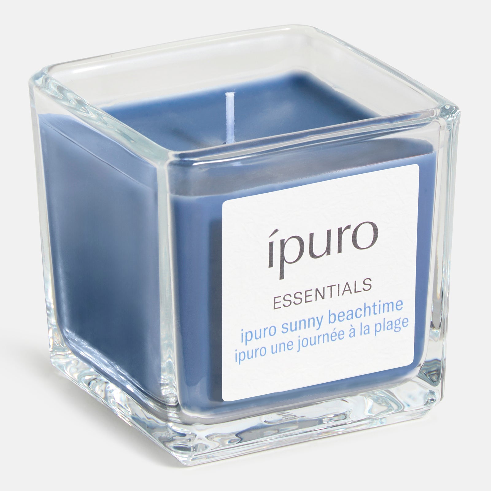 Ein quadratischer Kerzenhalter aus Glas enthält eine blaue Wachskerze. Auf dem Etikett steht: ipuro Duftkerze sunny beachtime - perfekt für Strand, Sommer und Sonne.