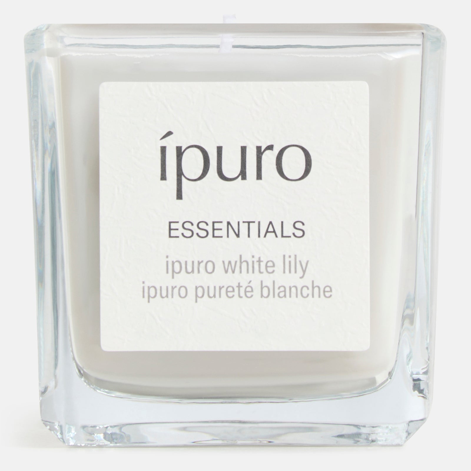 Die Duftkerze ipuro white lily von ipuro ist eine quadratische Glaskerze mit weißem Wachs und einem einzelnen Docht, die ein blumiges Dufterlebnis mit zarter weißer Blüte liefert.