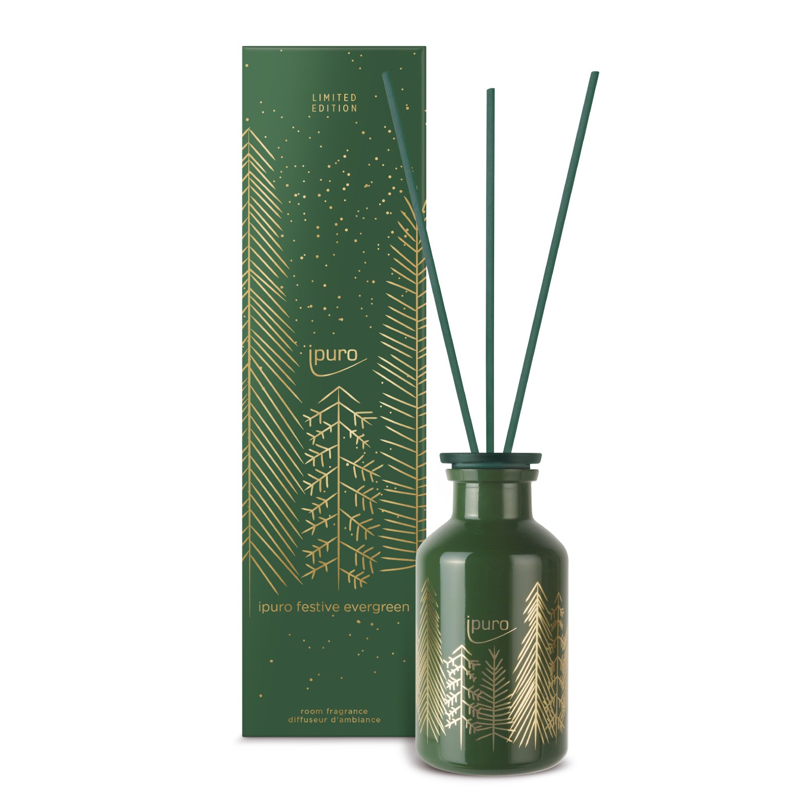 Ein grüner Glasflakon von ipuro festlicher immergrüner Raumduft 240ml mit drei Diffusorblättern steht neben einer passenden grün-goldenen LIMITED EDITION Box, die mit immergrünen Bäumen und goldenen Punkten verziert ist.